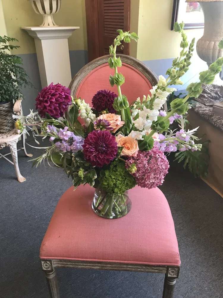 Mixed floral arrangement in a clear glass vase with pink, purple, white, and peach blooms