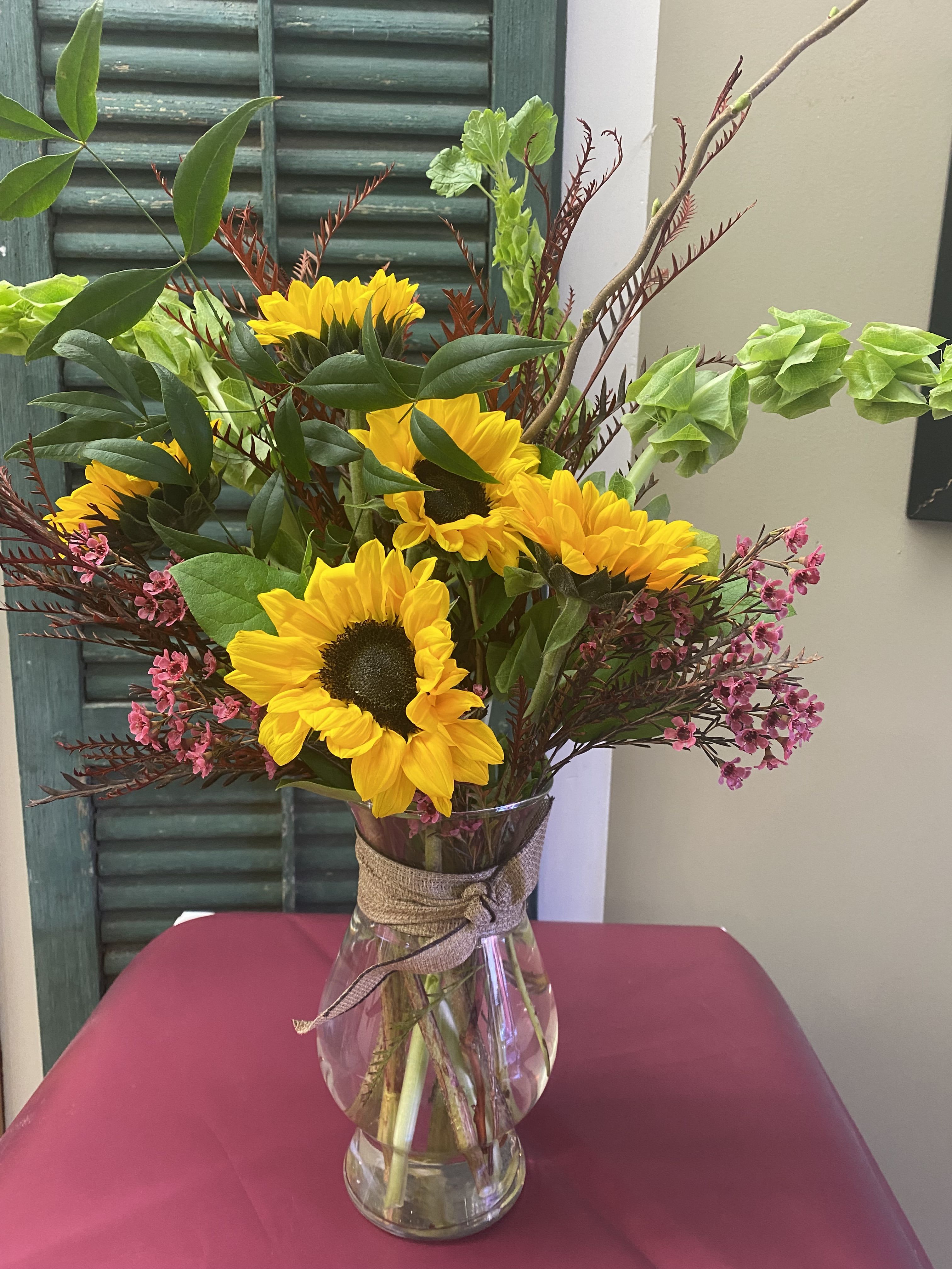 Sunflower bouquet in a clear glass vase with pink filler flowers