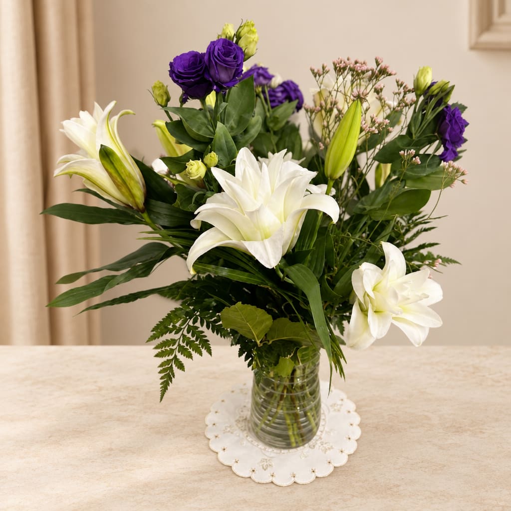 White lilies and purple roses in a clear glass vase