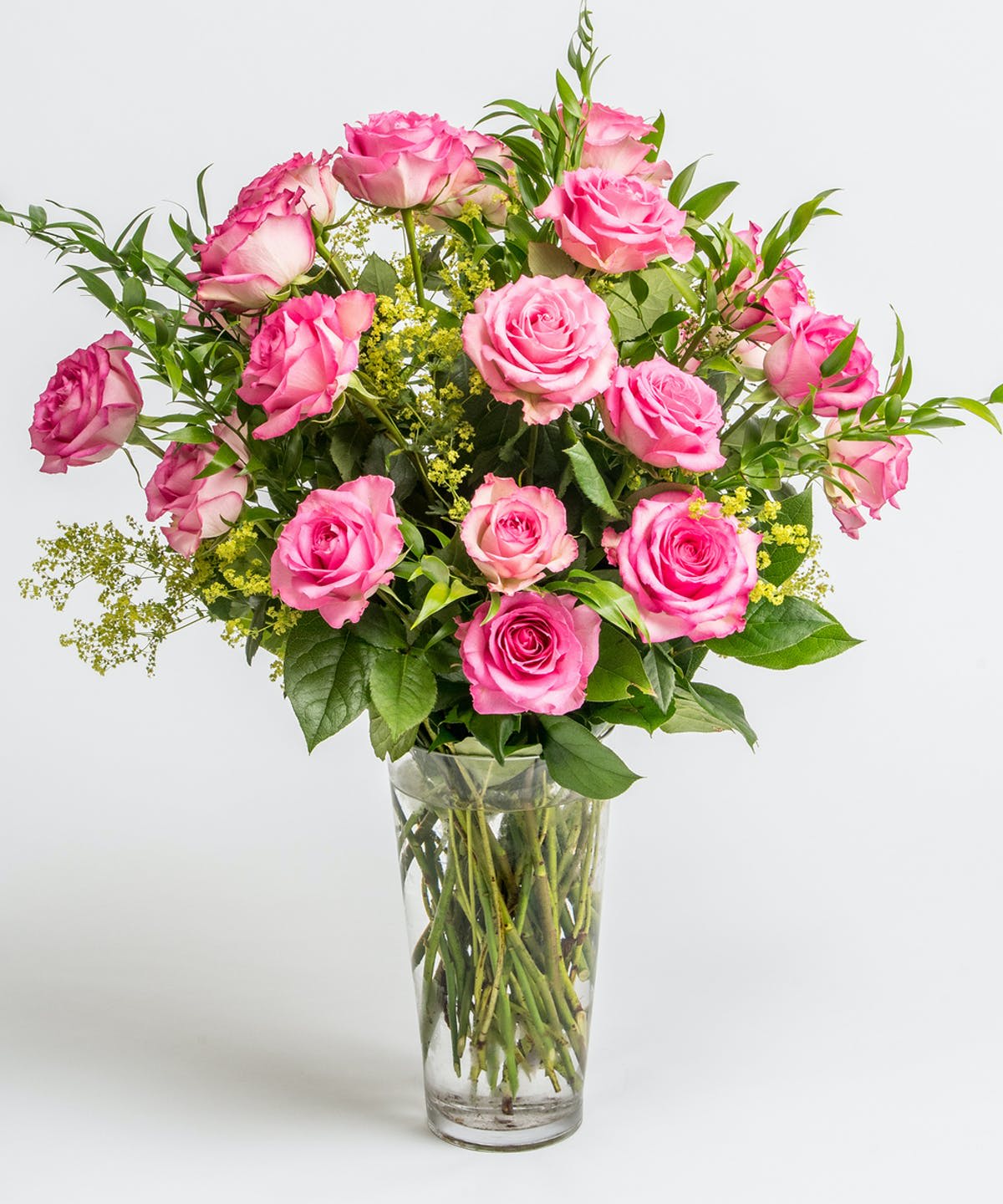 Pink roses in a clear glass vase with green filler