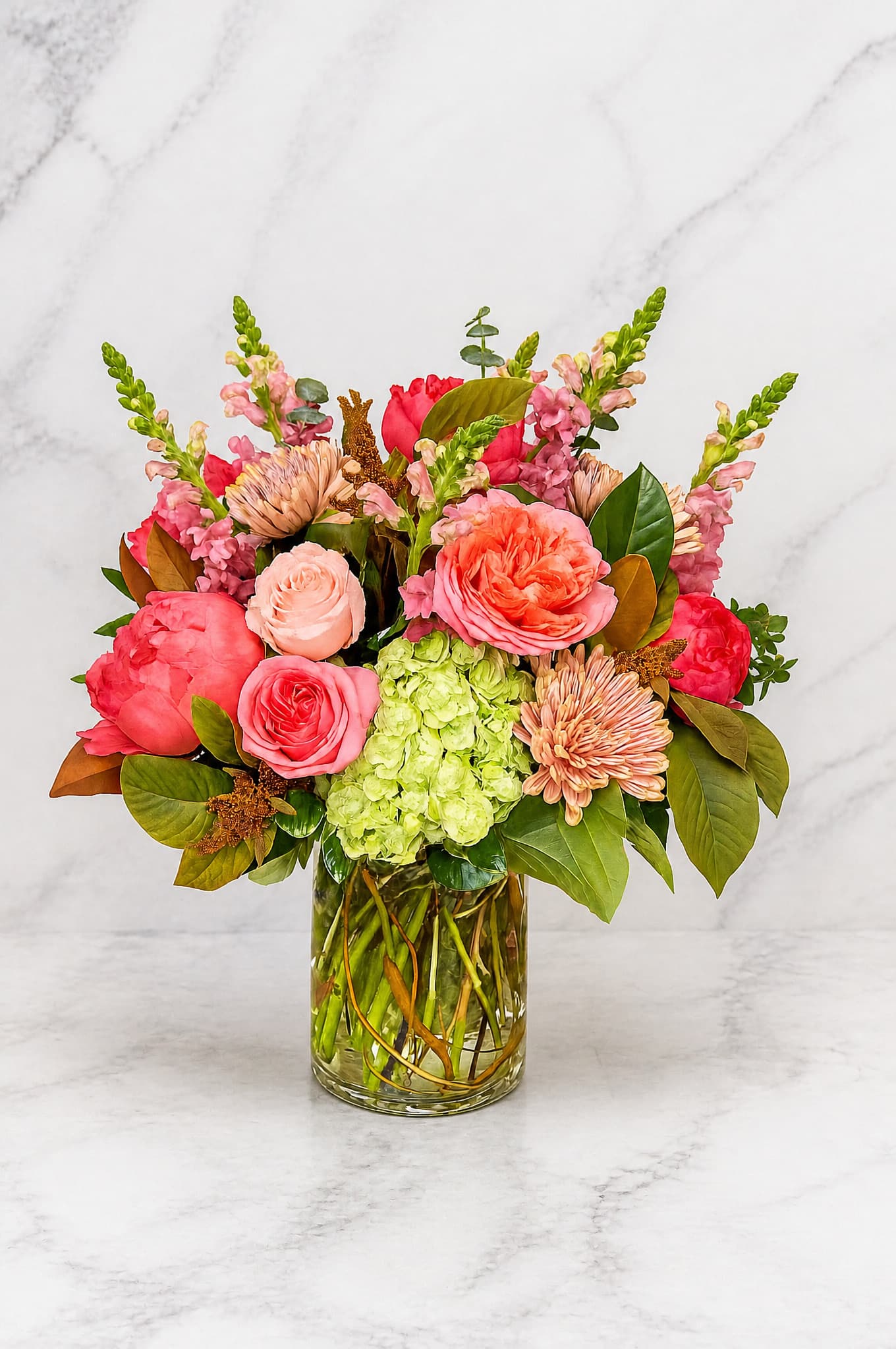 Mixed pink and coral flowers arranged in a clear glass vase