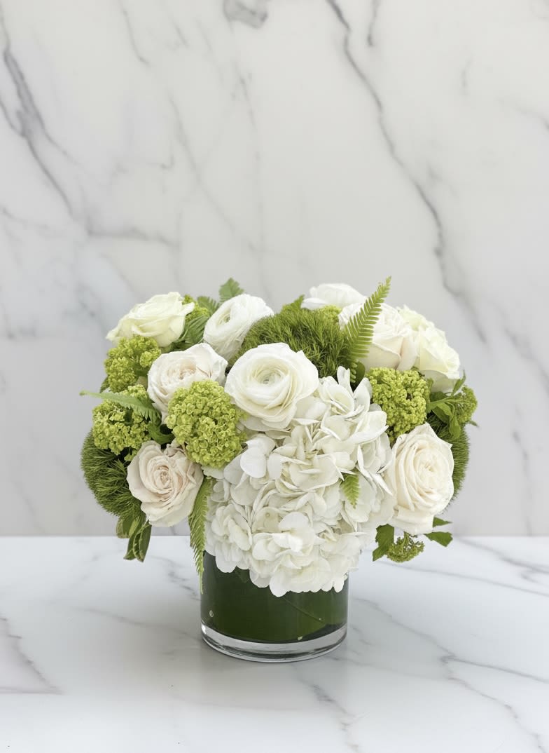 The Marilyn - The Marilyn — A luxurious white flower arrangement featuring premium roses, hydrangeas, and fresh green accents. Designed in a modern glass vase, this elegant bouquet embodies timeless beauty and sophistication. Perfect for weddings, anniversaries, and upscale events, The Marilyn adds a touch of classic charm to any setting. Handcrafted with care by our San Francisco florist for same-day delivery.