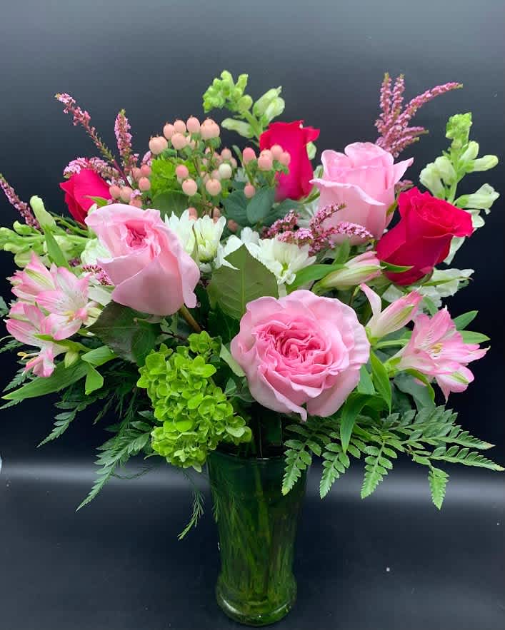 Pink roses and alstroemeria in a green glass vase