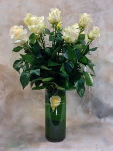 White roses in a tall green vase with a single rose on the front