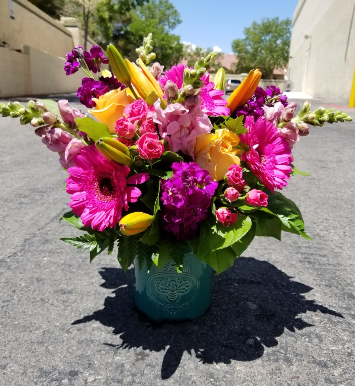 Bright mixed bouquet in a teal vase with pink, yellow, and purple flowers