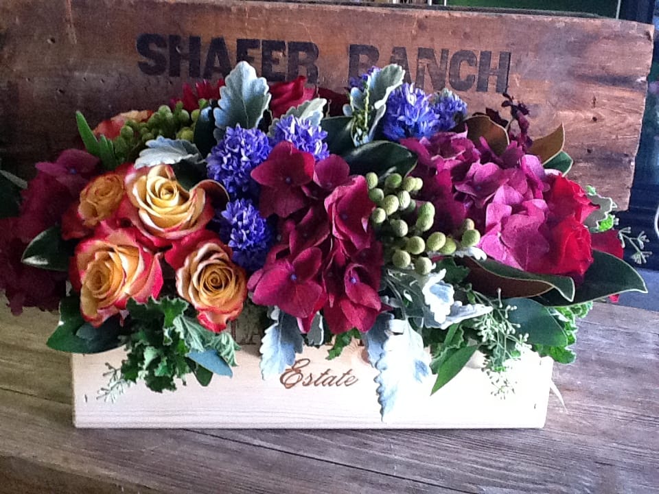 Mixed floral arrangement in a wooden box with roses and hydrangeas