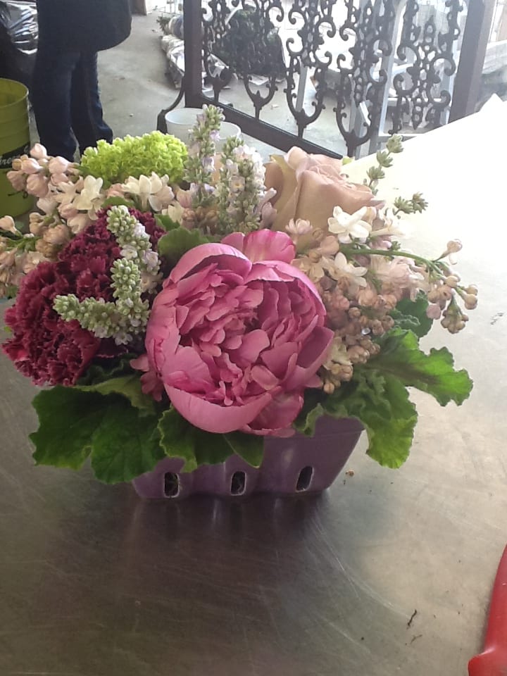 Pink peony arrangement in a purple container with mixed blooms
