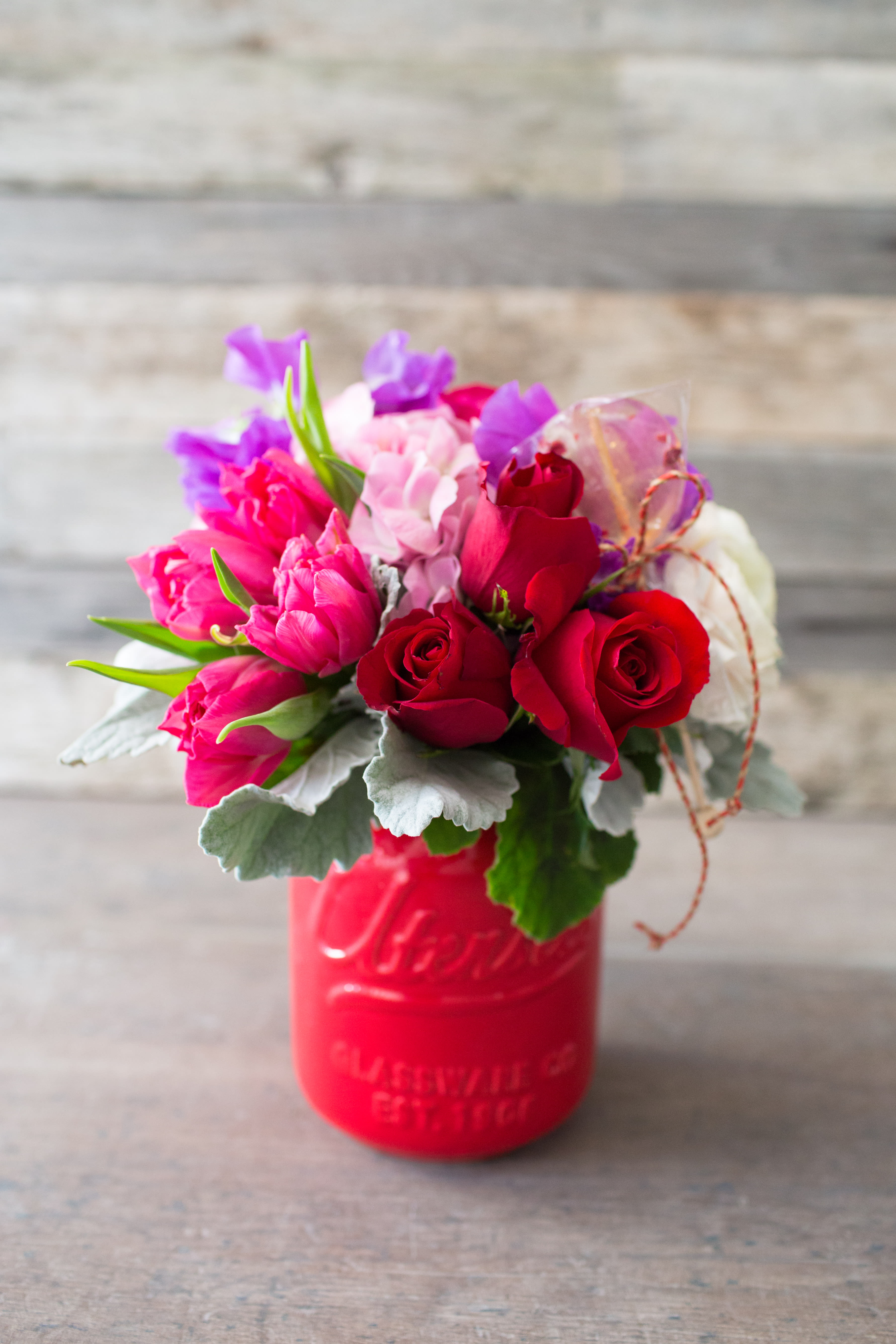 Bouquet of red and pink roses in a red mason jar