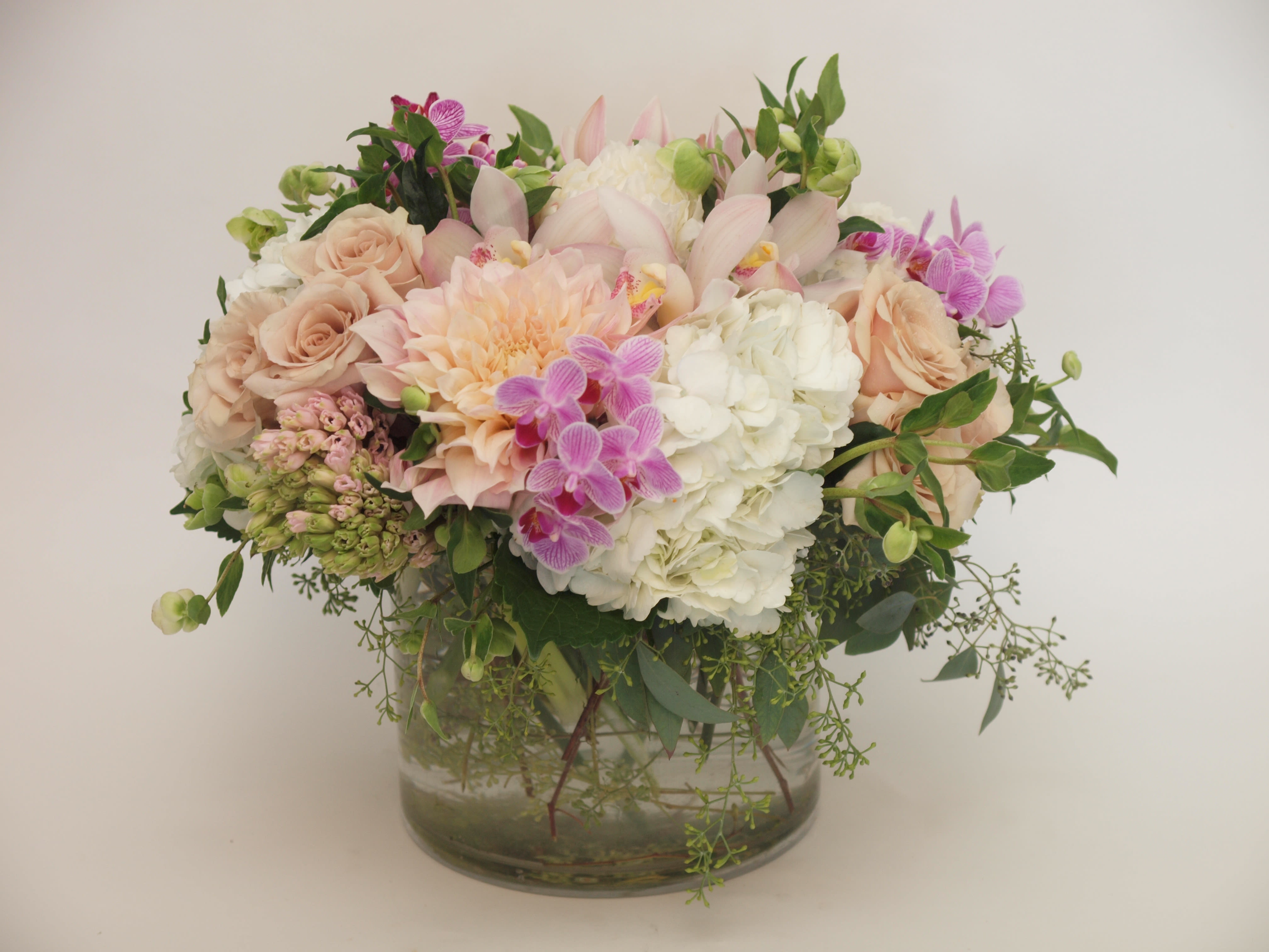 Pastel bouquet of roses, hydrangeas, orchids, and dahlias in a glass vase