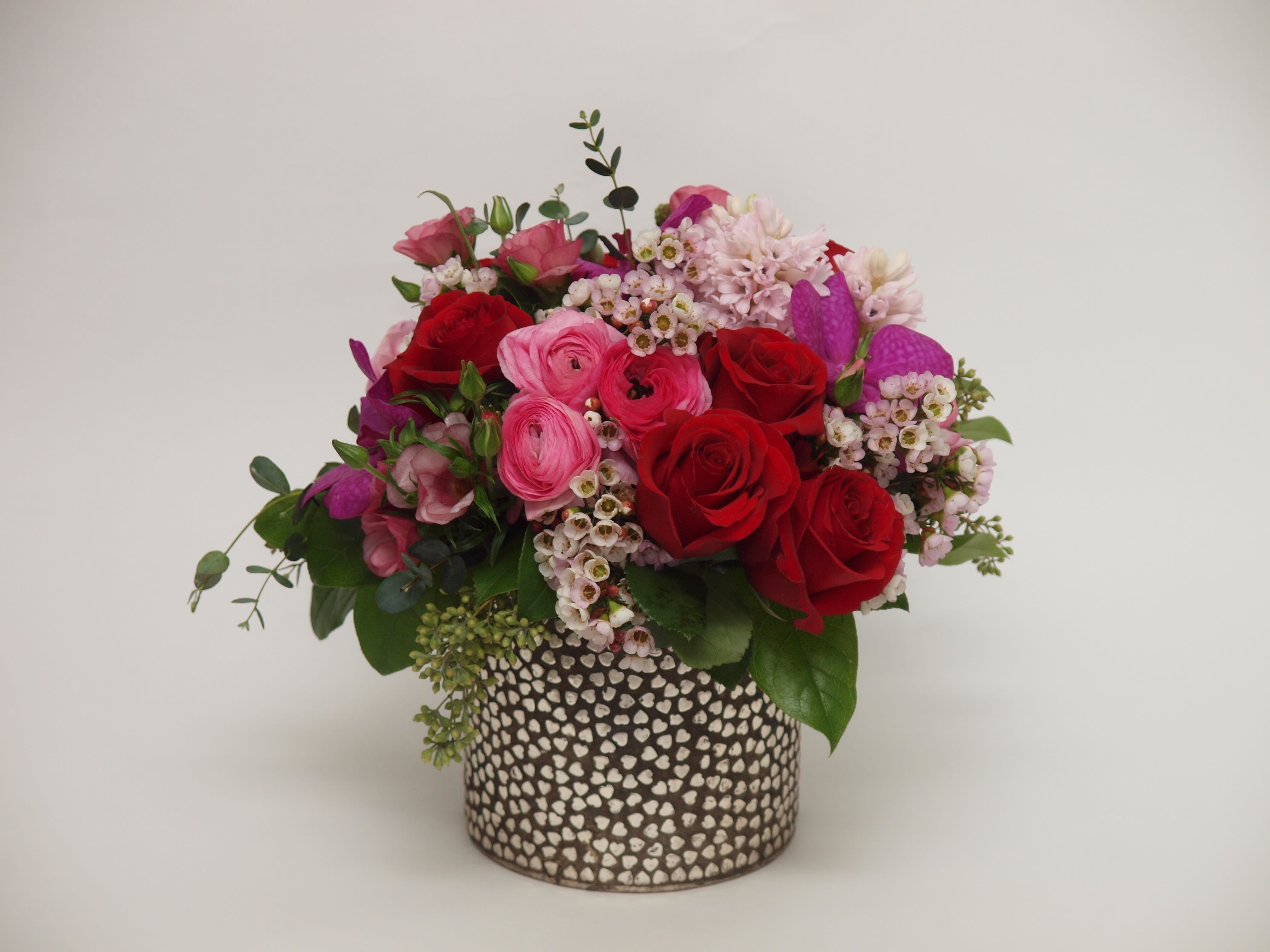 Red and pink roses arranged in a patterned vase