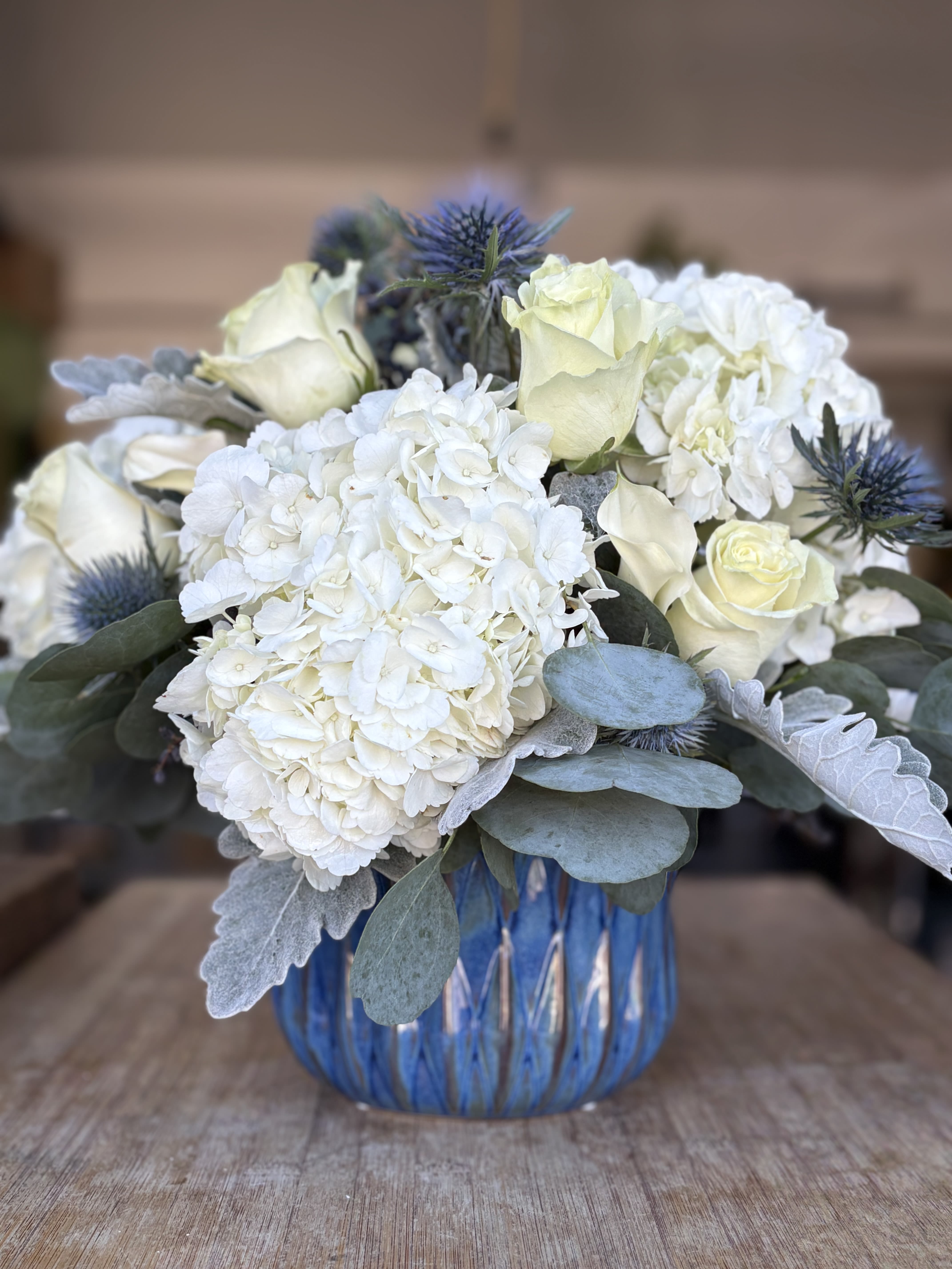 White hydrangeas and pale roses in a blue glass vase