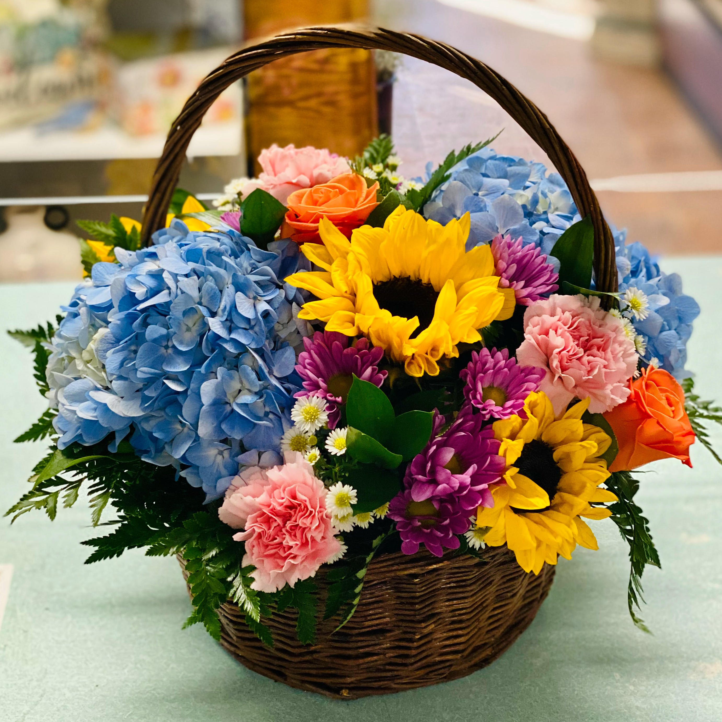 Basket of mixed flowers with sunflowers, hydrangeas, roses, and carnations