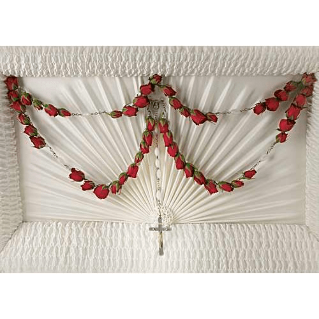 White fan-shaped funeral spray with red rose garlands and a cross pendant