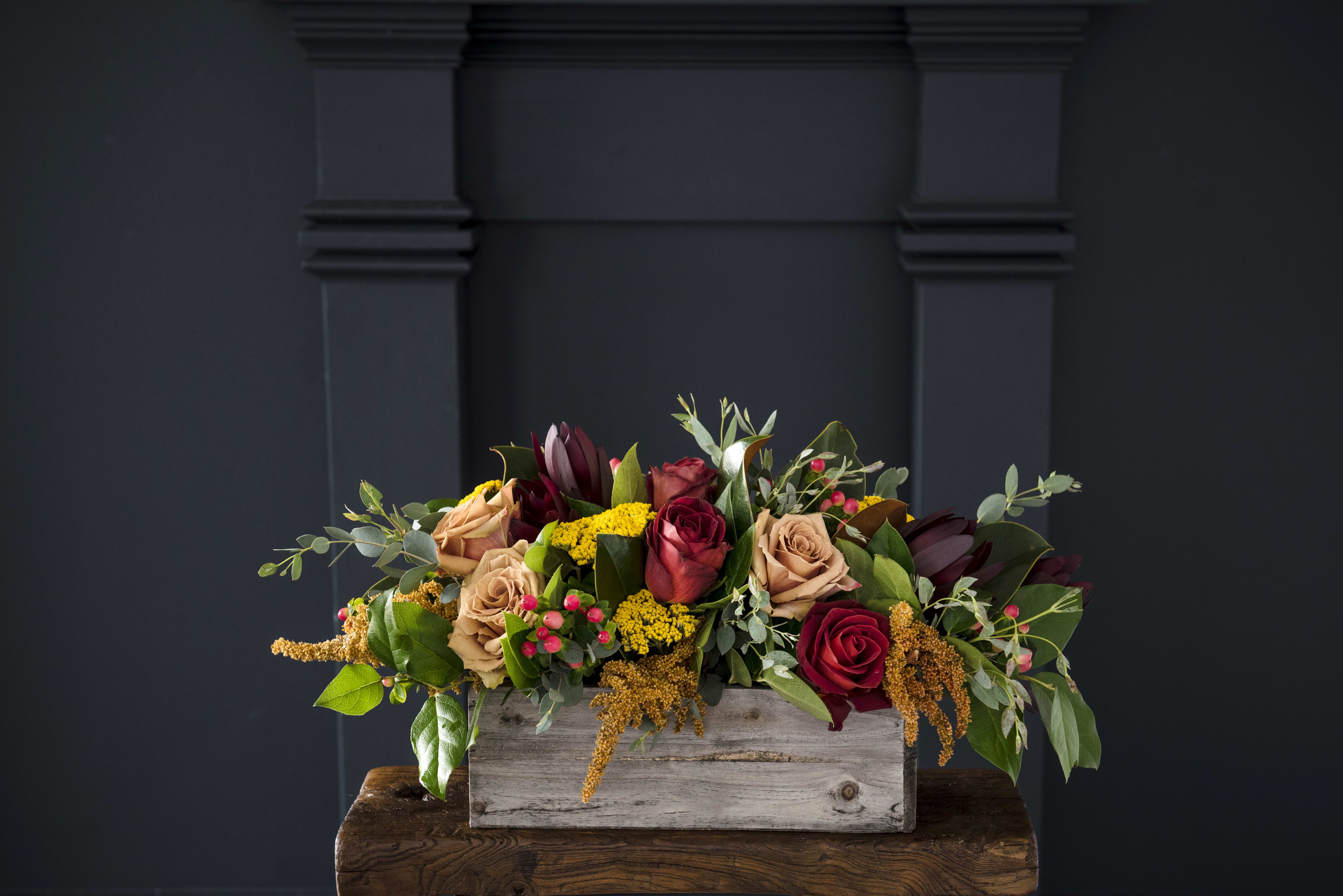 Mixed roses in a rustic wooden box with greenery and yellow filler flowers