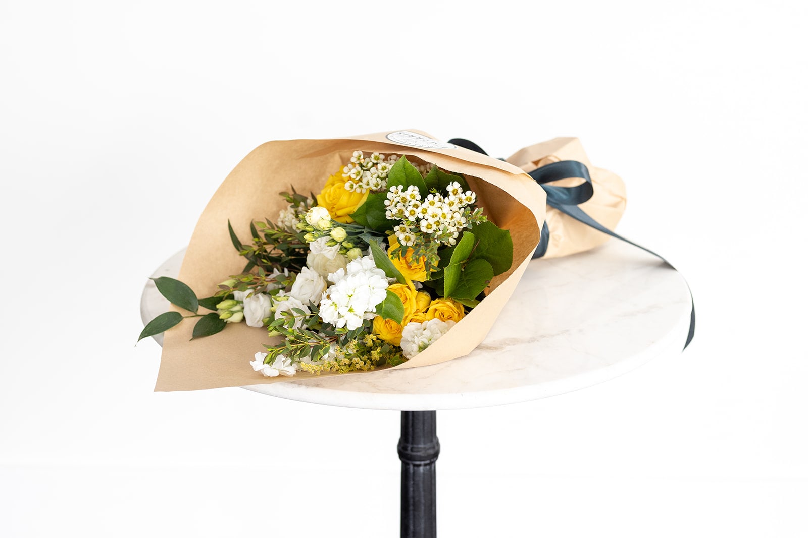 Bouquet of yellow and white flowers wrapped in kraft paper