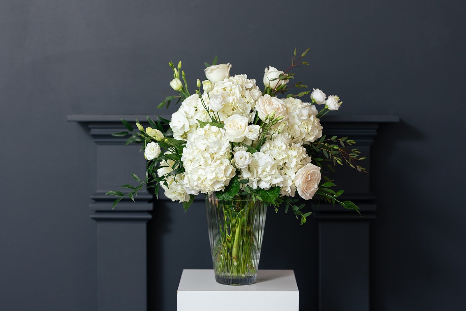 White roses and hydrangeas arranged in a clear glass vase