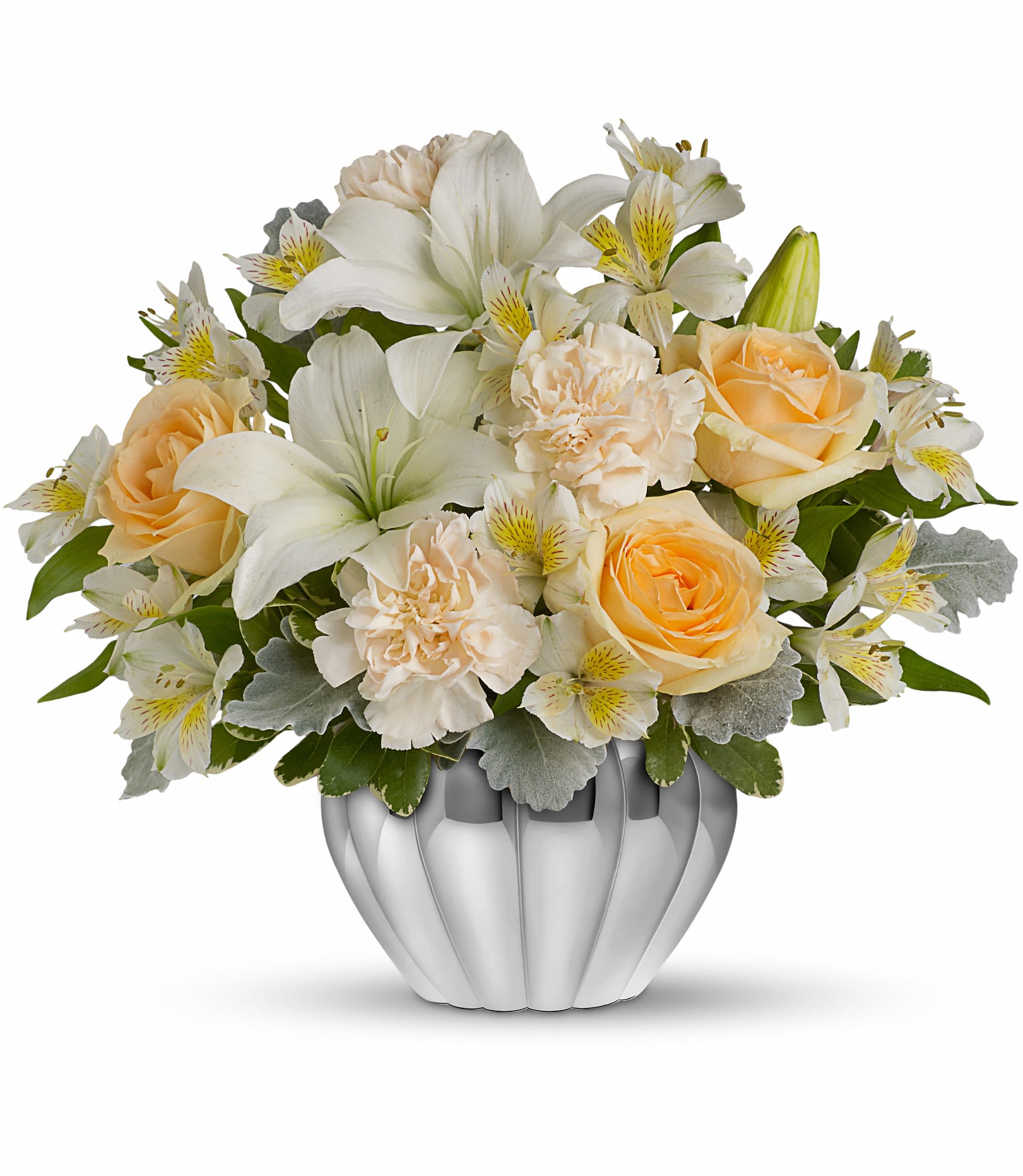 Low arrangement of white lilies, peach roses, and cream flowers in a round silver vase
