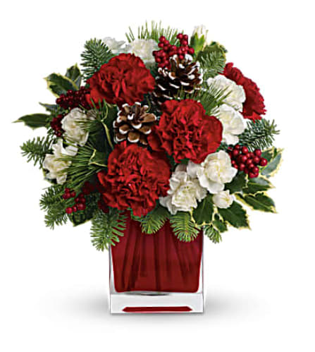 Red and white floral arrangement in a clear square vase with pinecones