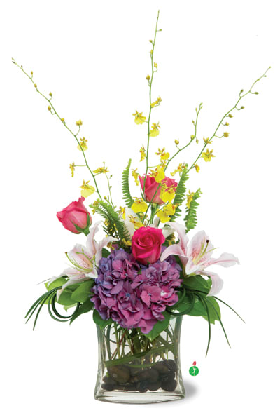 Tall arrangement with pink roses, lilies, purple hydrangea and yellow orchids in a glass vase with stones