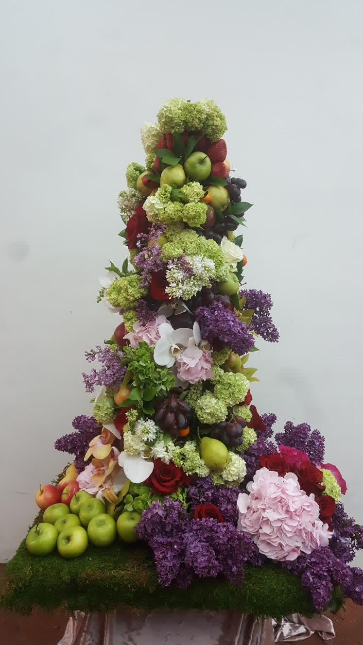 Tiered floral display with fruit, hydrangeas, roses, and orchids