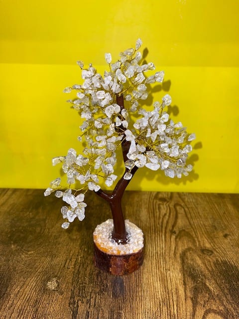 Decorative crystal tree on a wooden base against a yellow background