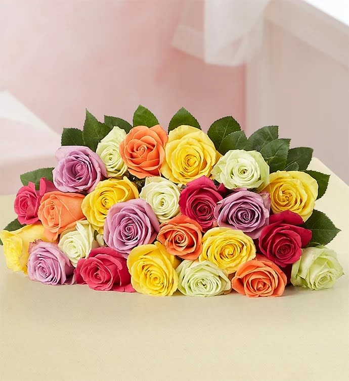 A bouquet of multicolored roses with dark green leaves.