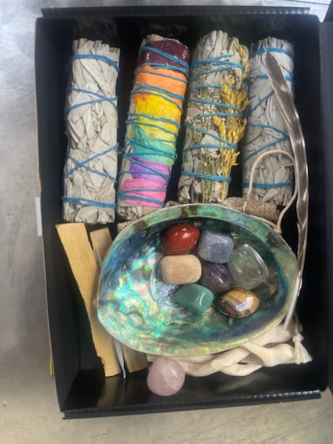 Box of bundled sage sticks, crystals, and an abalone shell