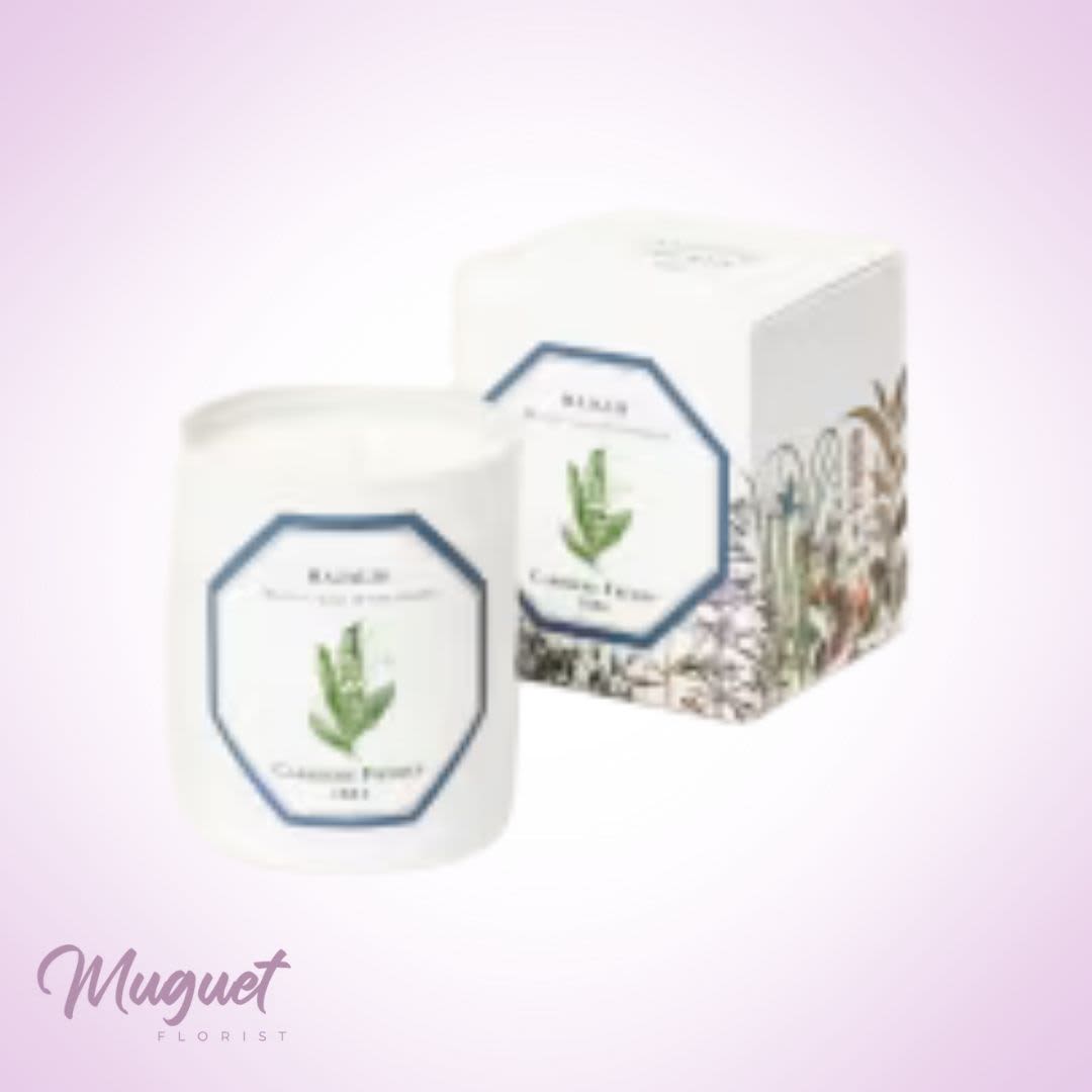 White candle jar and matching box with floral label on a pink background