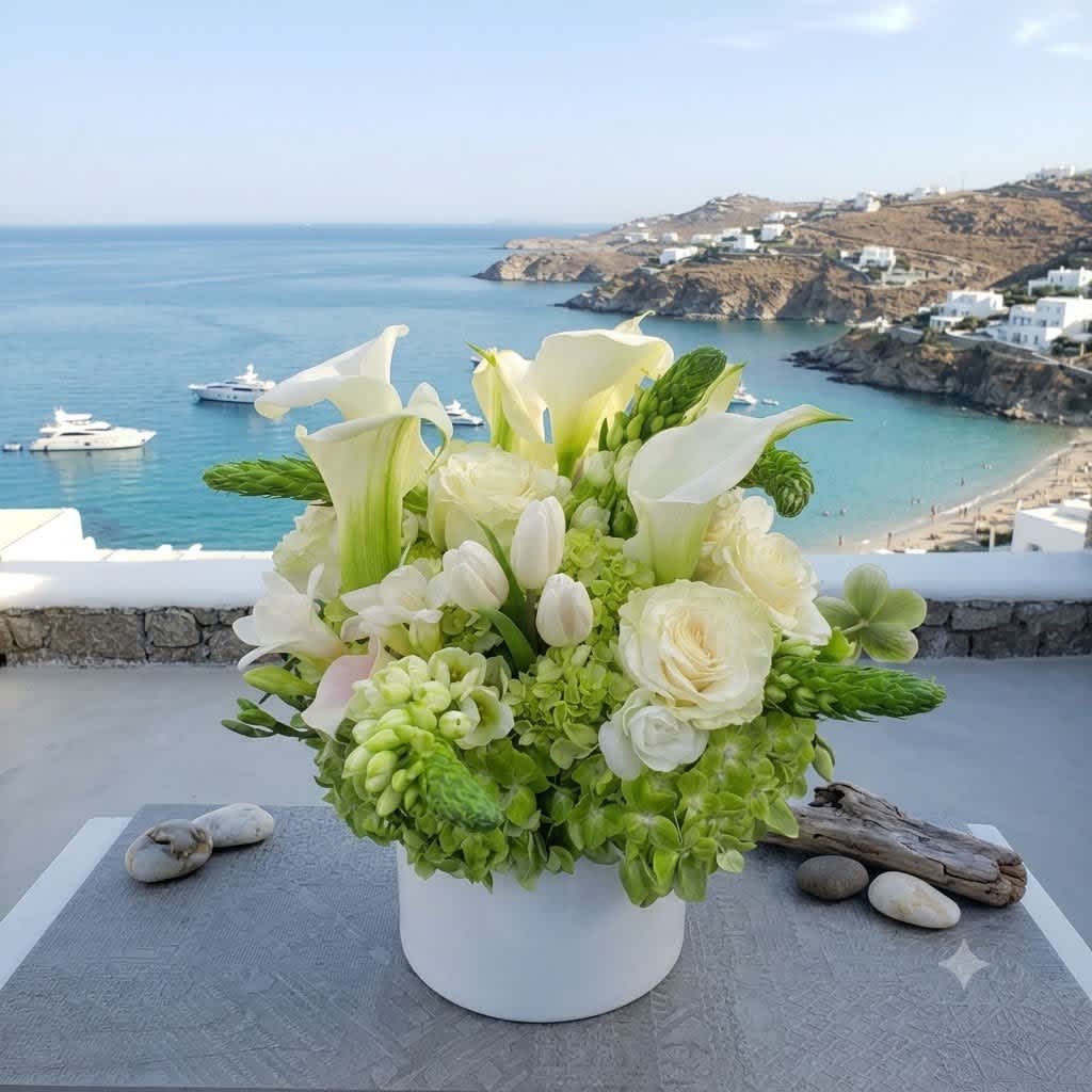 White and green floral arrangement in a white vase with calla lilies and roses