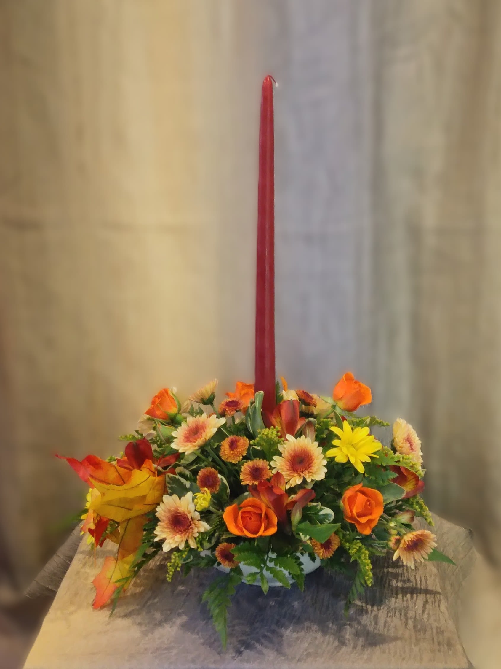 Autumn floral centerpiece with a tall red taper candle