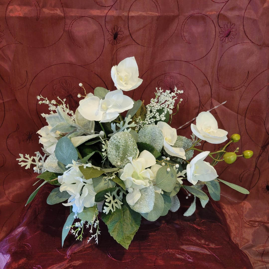 White orchid bouquet with eucalyptus and glittered accents on a burgundy backdrop