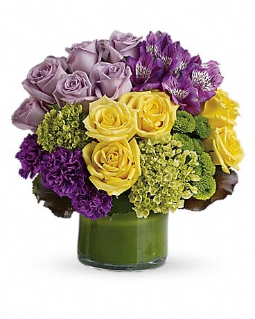 Bouquet of yellow, lavender, and purple flowers in a glass vase