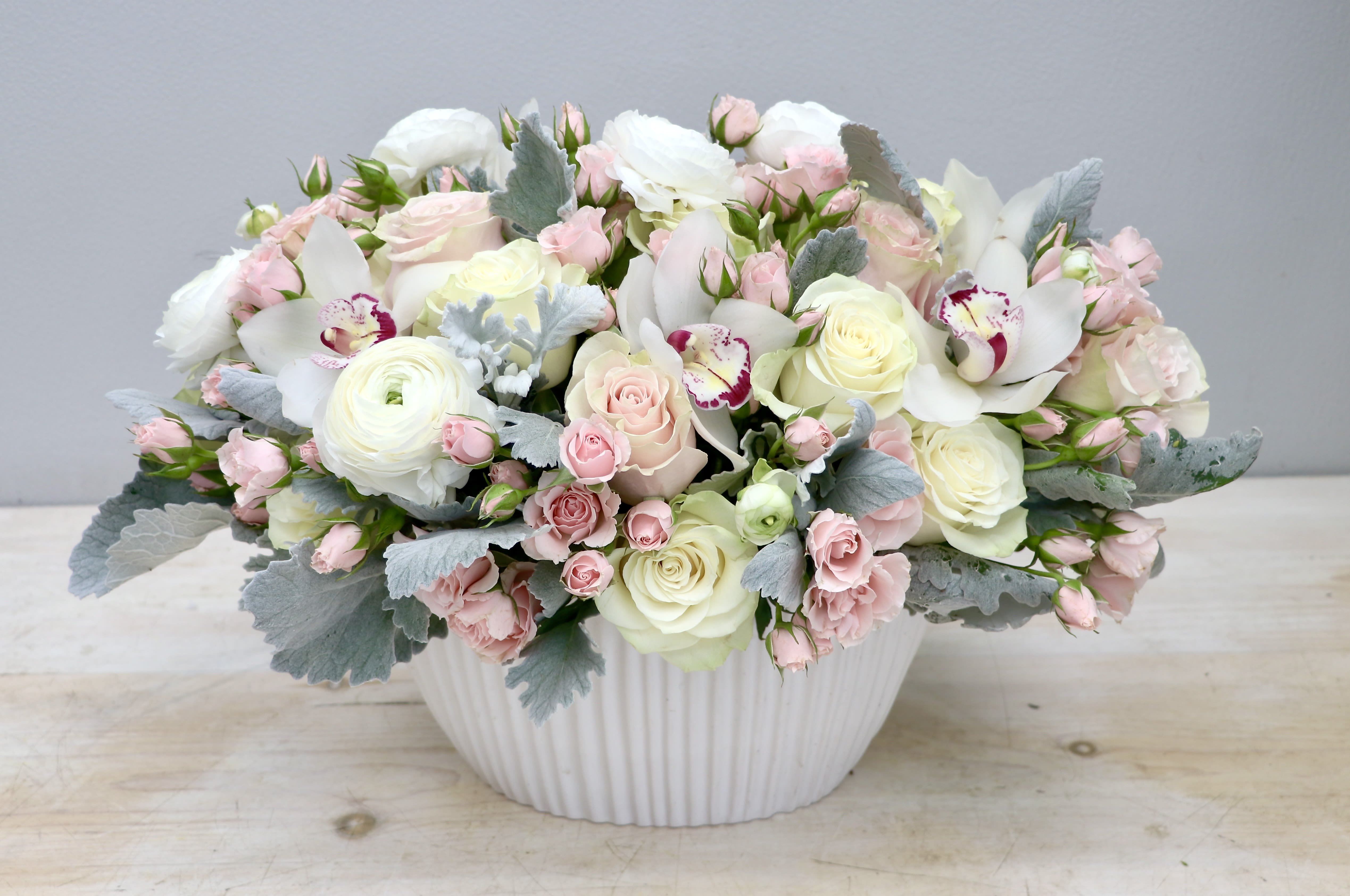 Low pastel arrangement of white and blush flowers in a white ceramic bowl