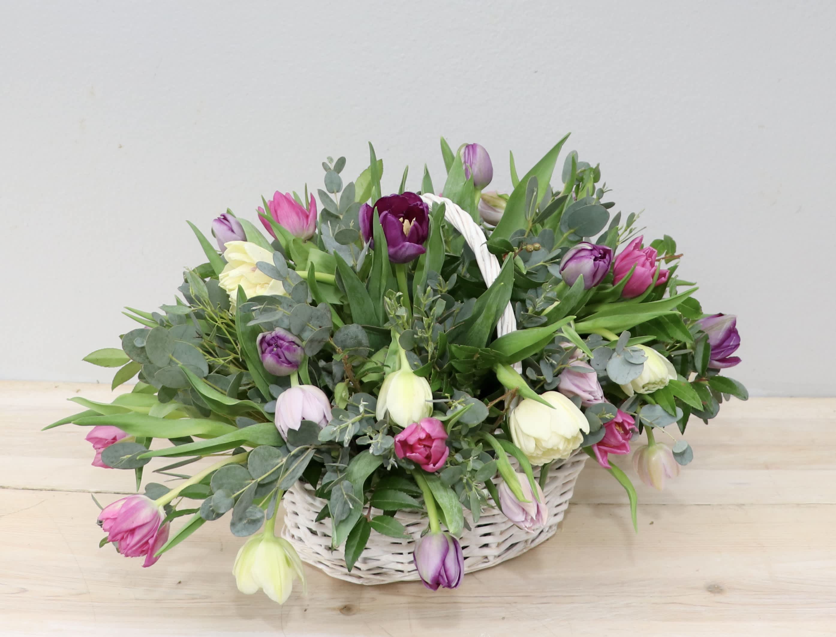 Basket of pink, purple, and white tulips with greenery