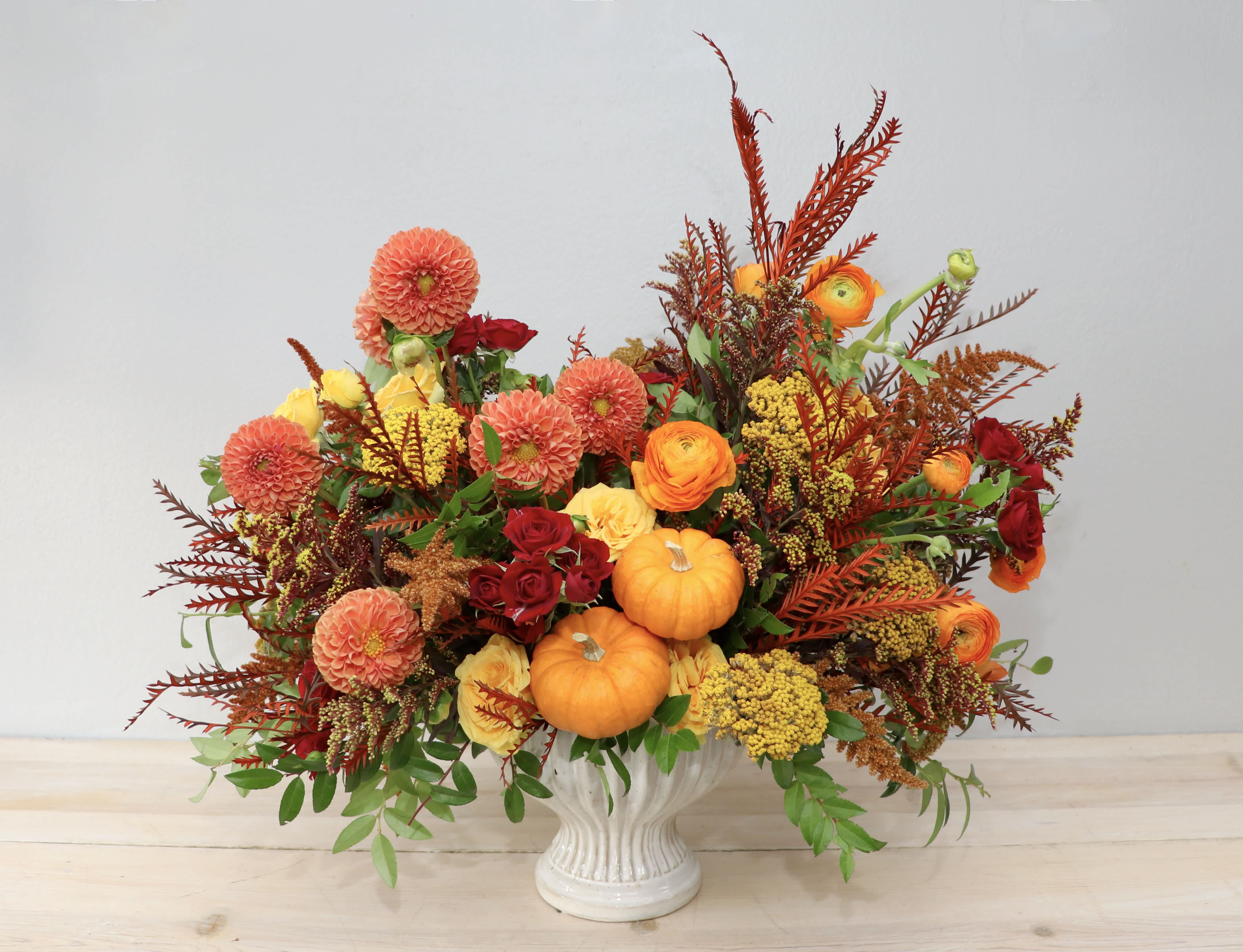 Autumn floral arrangement with pumpkins in a white vase