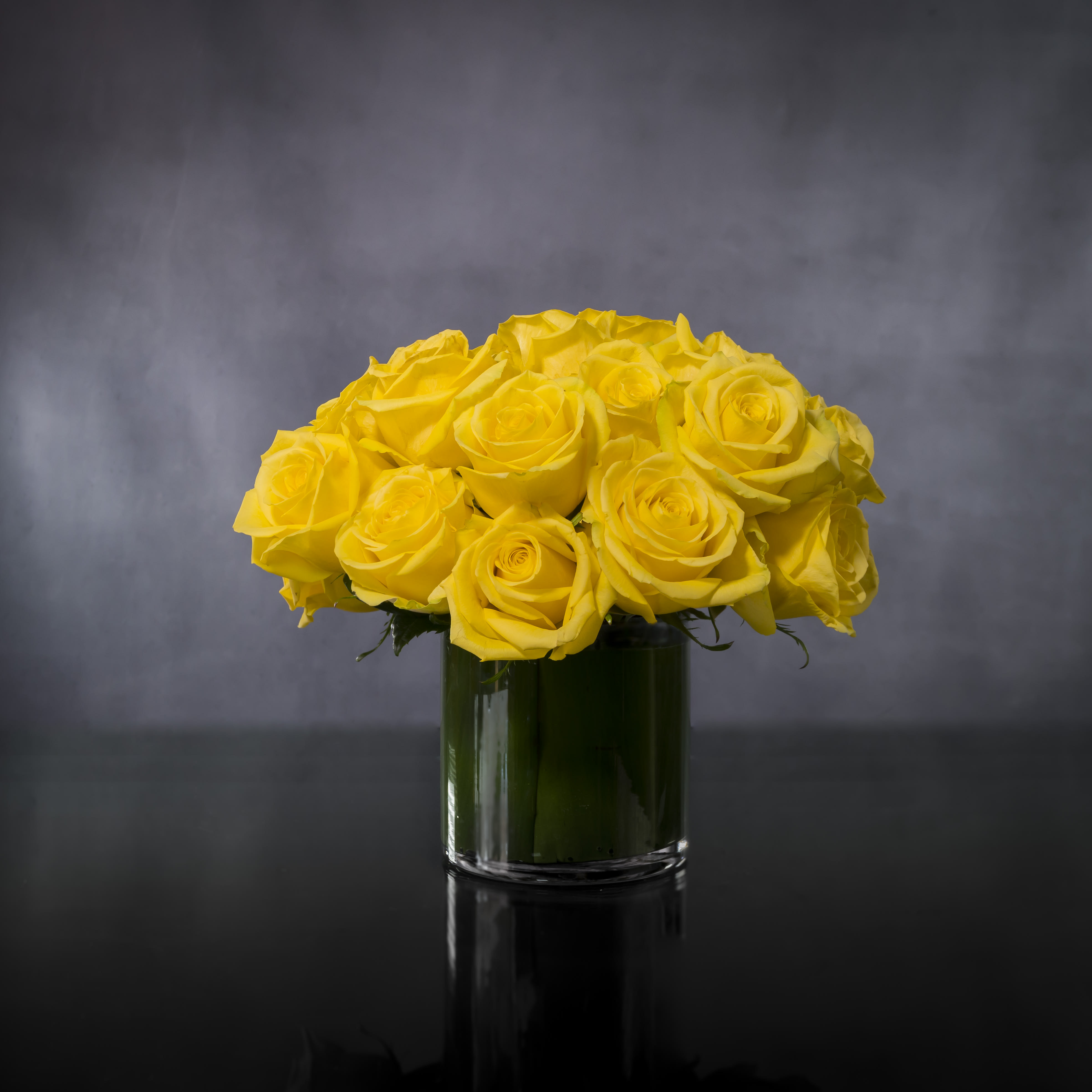 Sweet Sunrise - An Arrangement that is sure to be Bright, vibrant and sunny! An array of yellow Roses, the color of friendship, are sure to brighten anyone's day. Send good wishes and happiness with 2 dozen lovely yellow roses clustered in a glass vase. 8" round  Standard : 2 Dozen Roses  Deluxe: 3 Dozen Roses  Premium: 4 Dozen Roses