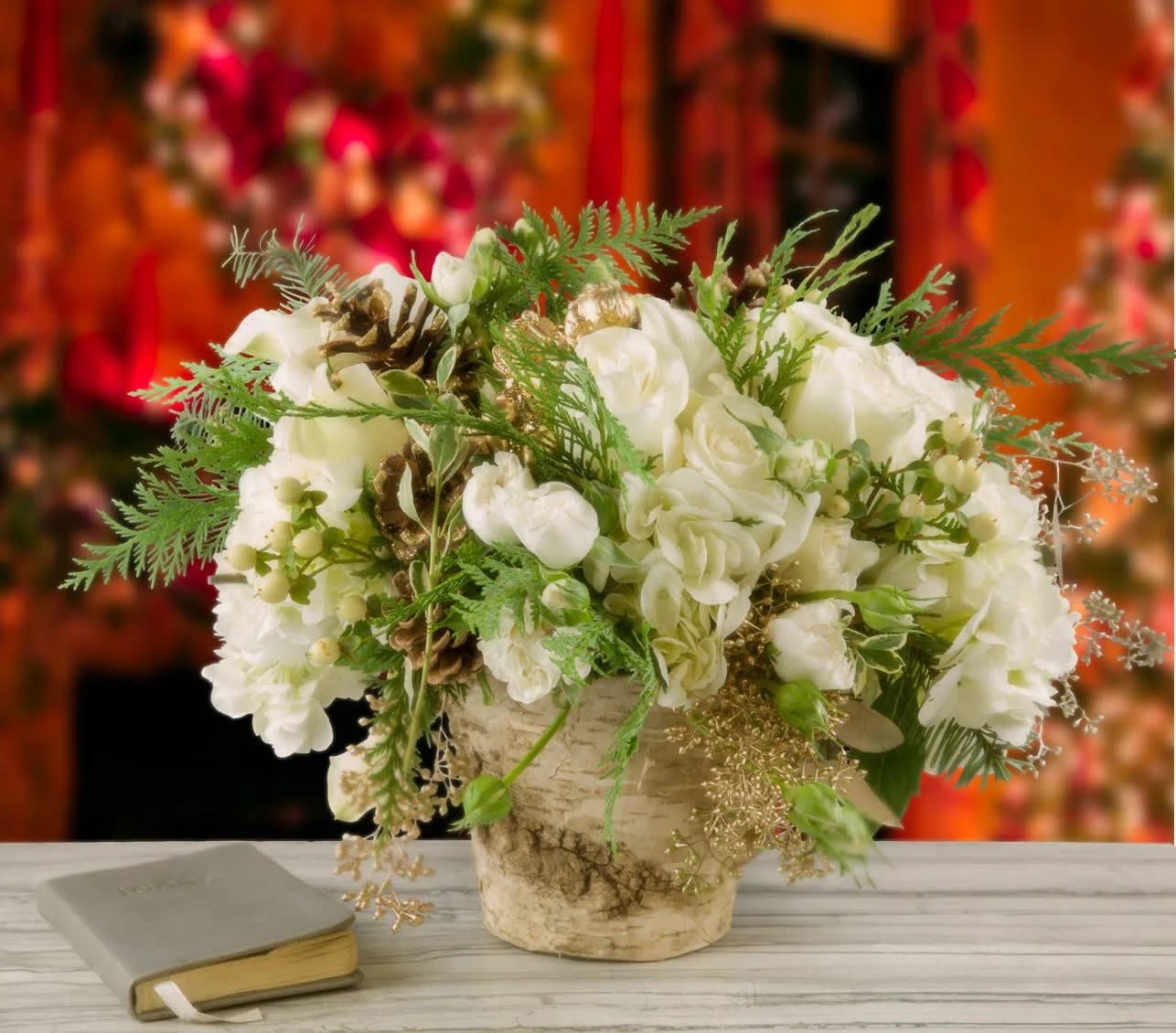White floral arrangement in a rustic vase beside a book
