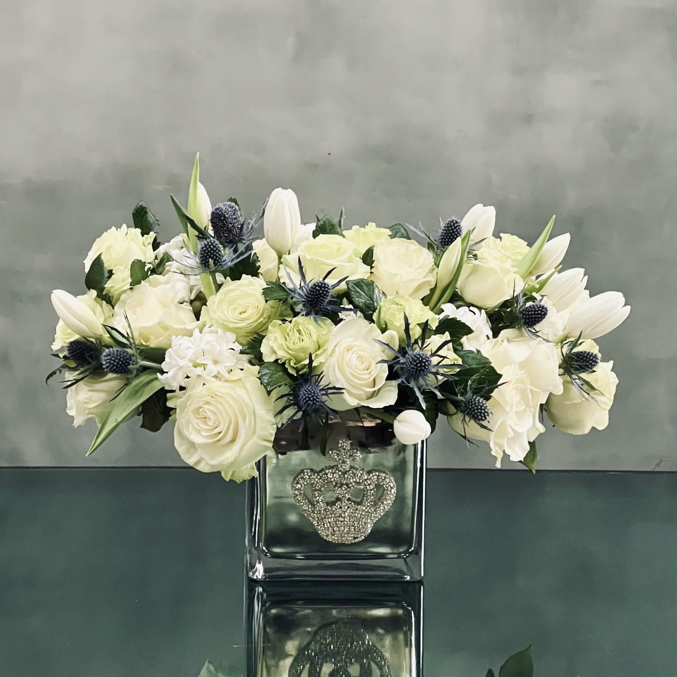 Ice Queen - A cluster of white tulips, roses, hyacinths and thistle in a bejeweled crown silver glass vase.