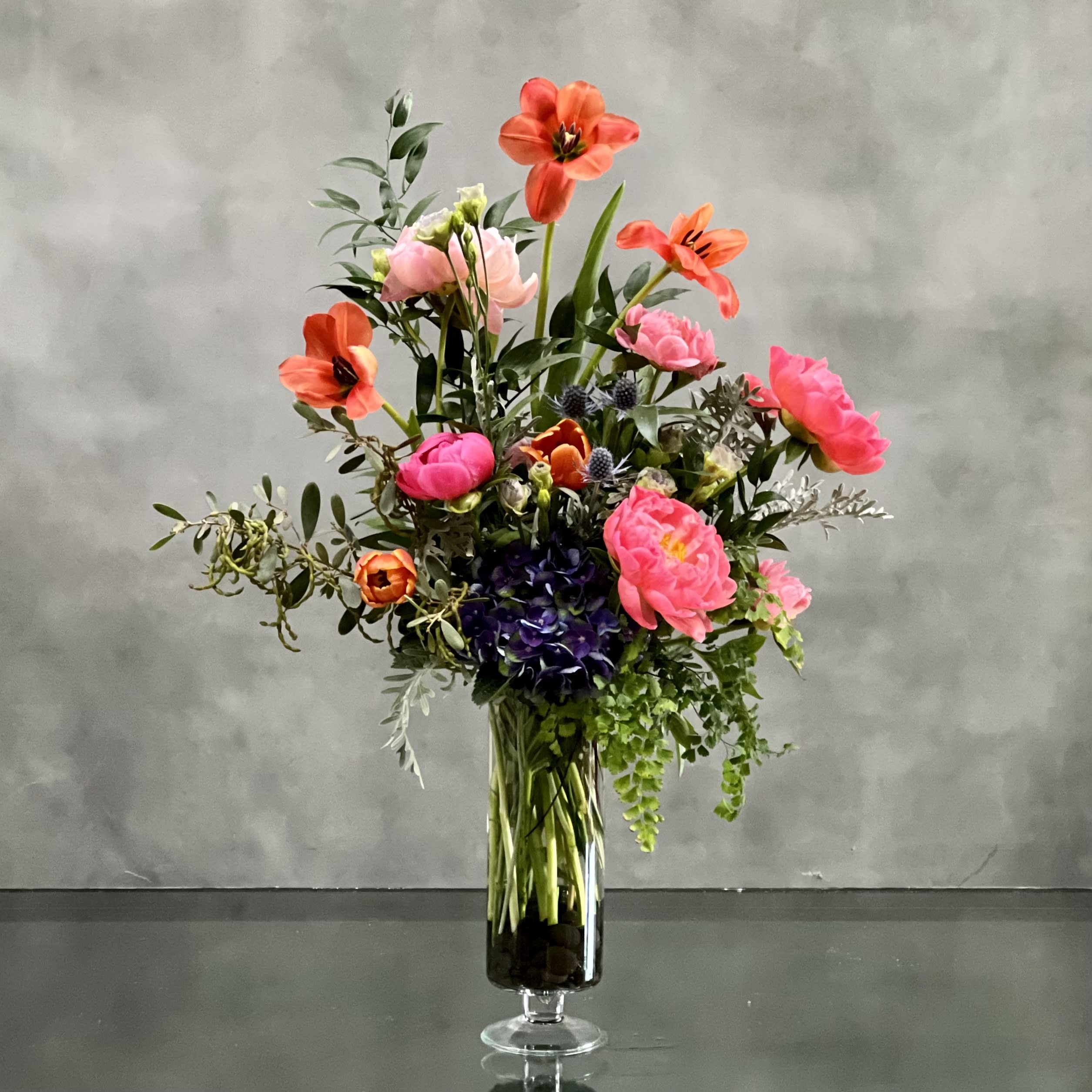 21st Century Women Designers Choice  - Fabulously faceted to catch anyone's eye! Bursting with  peonies, Tulips, and rare Bi Color Dutch Hydrangea as a dramatic accents. A whimsical arrangement that has an extra special touch.  Aprrox. 30" Tall and 20" Wide in a 11" Vase 