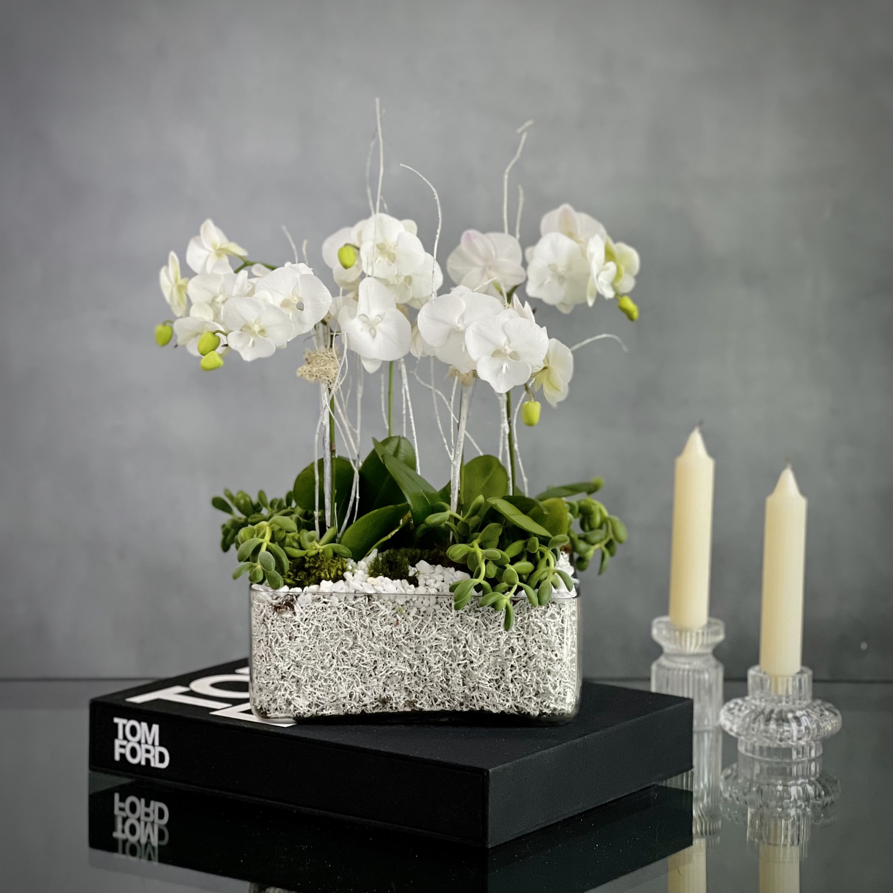 Color me White - 5 White Orchids in a Modern Low profile Square glass container decorated with white moss and White Marble.   Measurement   14" wide 16" tall Vase 10" X  4" tall
