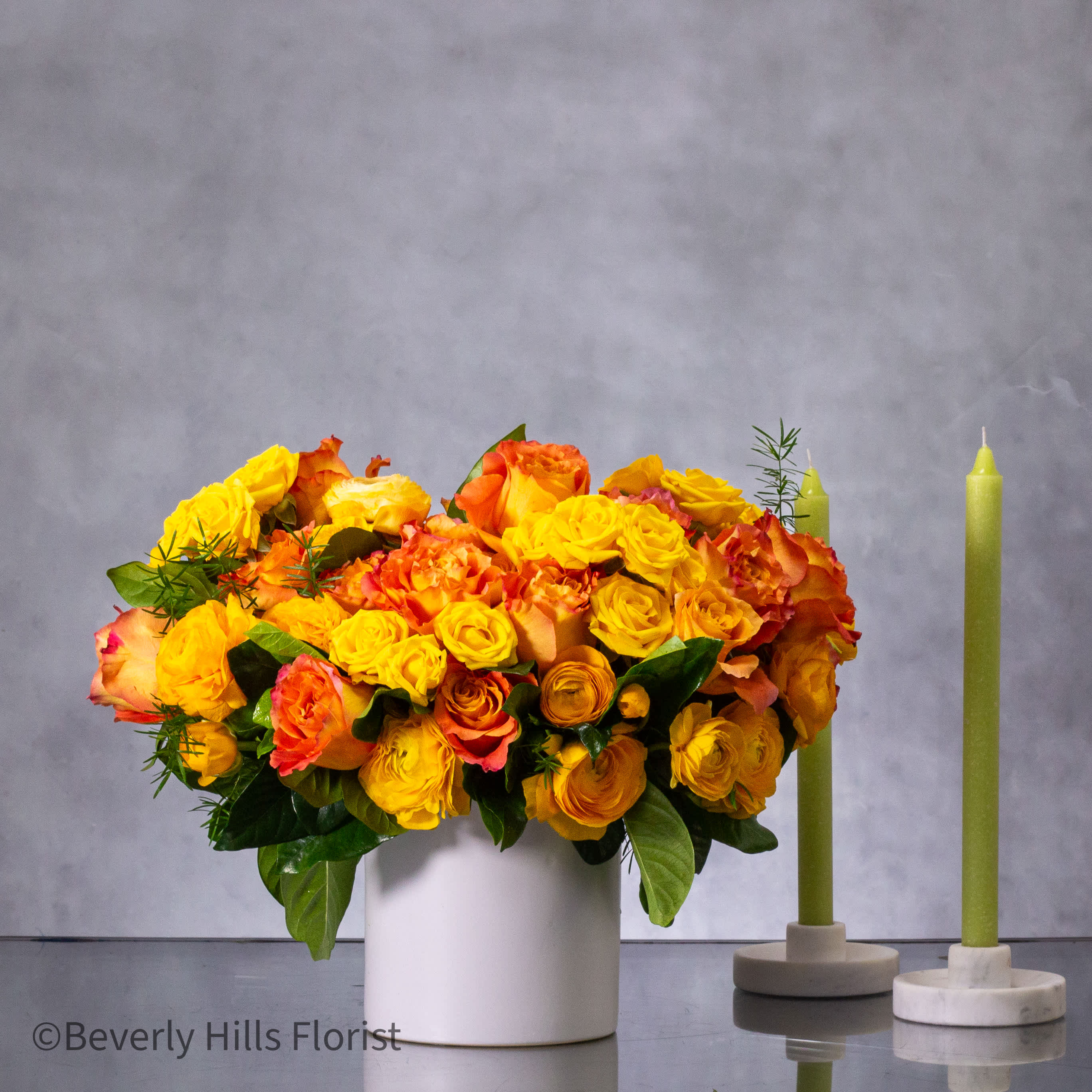 Citrus Sunset Elegance - Indulge in the radiant beauty of our "Citrus Sunset Elegance" floral arrangement, featuring a captivating blend of orange peel-colored blooms arranged in a pristine white ceramic vase. This compact arrangement, approximately 10 inches wide, exudes a vibrant and graceful allure, perfect for same-day delivery in Los Angeles and nearby cities.  Crafted to convey warmth and sophistication, this arrangement is a harmonious mix of blooms that will brighten any space with its vivid hues. Whether as a thoughtful gesture or a charming addition to your decor, "Citrus Sunset Elegance" promises to delight and mesmerize with its stunning display of compact, fresh flowers.