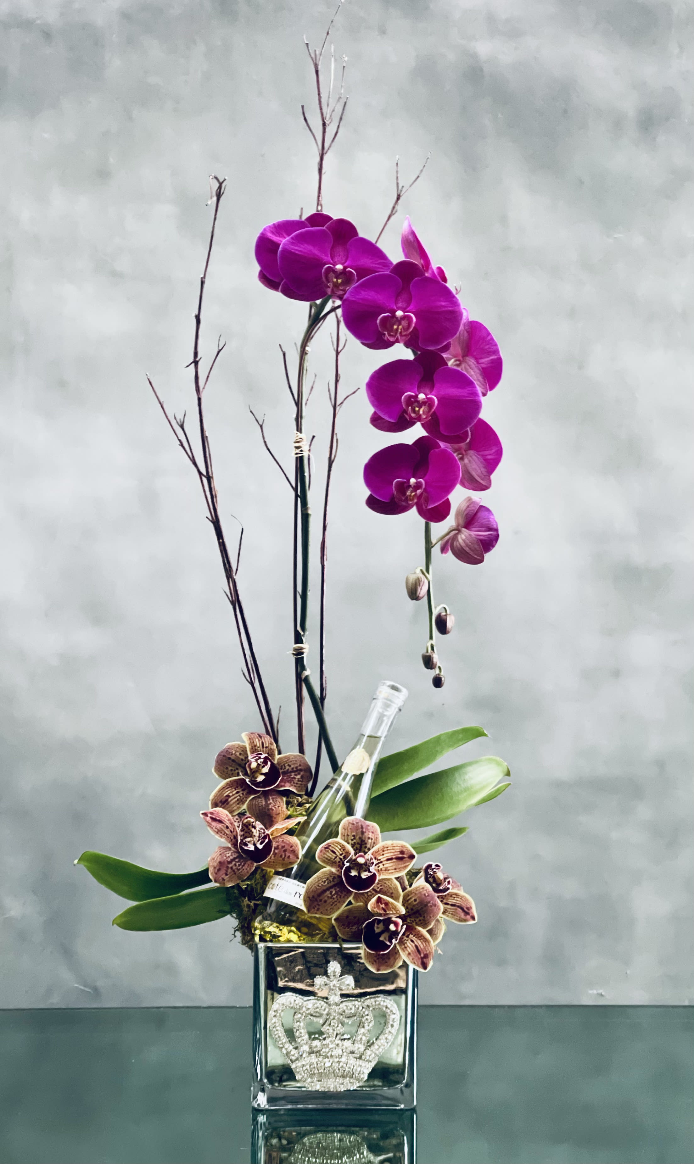 Duo Orchid Royale - Pasadena Florist  - This duo orchid arrangement with Amethyst cascading orchid, Cymbidium orchids and a half bottle Cotes de Roses Chardonnay are nested in a crown jeweled vase. Please note that Orchid color may differ depending on the season but it will still would have the purple hue. 