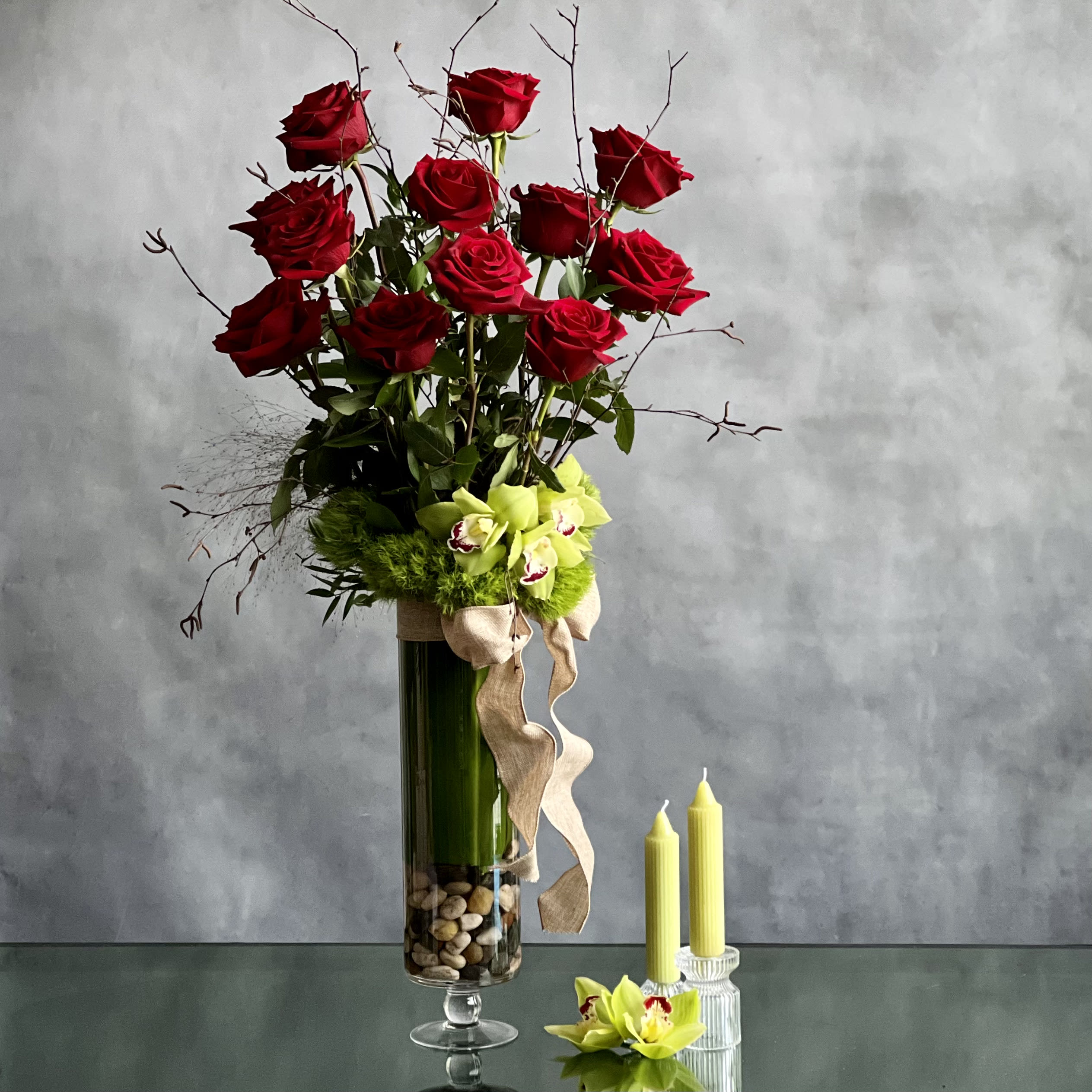 12 Roses Standing Tall - Pasadena Florist - Simple elegance.... this lovely glass footed vase holds 1 dozen Imported Ecuadorian Roses nested with moss and matching colored cymbidium orchids. A classic look that always impresses.   Please state the COLOR of roses upon checkout on Florist Notes  Standard: One Dozen Imported Ecuadorian roses  Deluxe: Two Dozen Imported Ecuadorian roses 