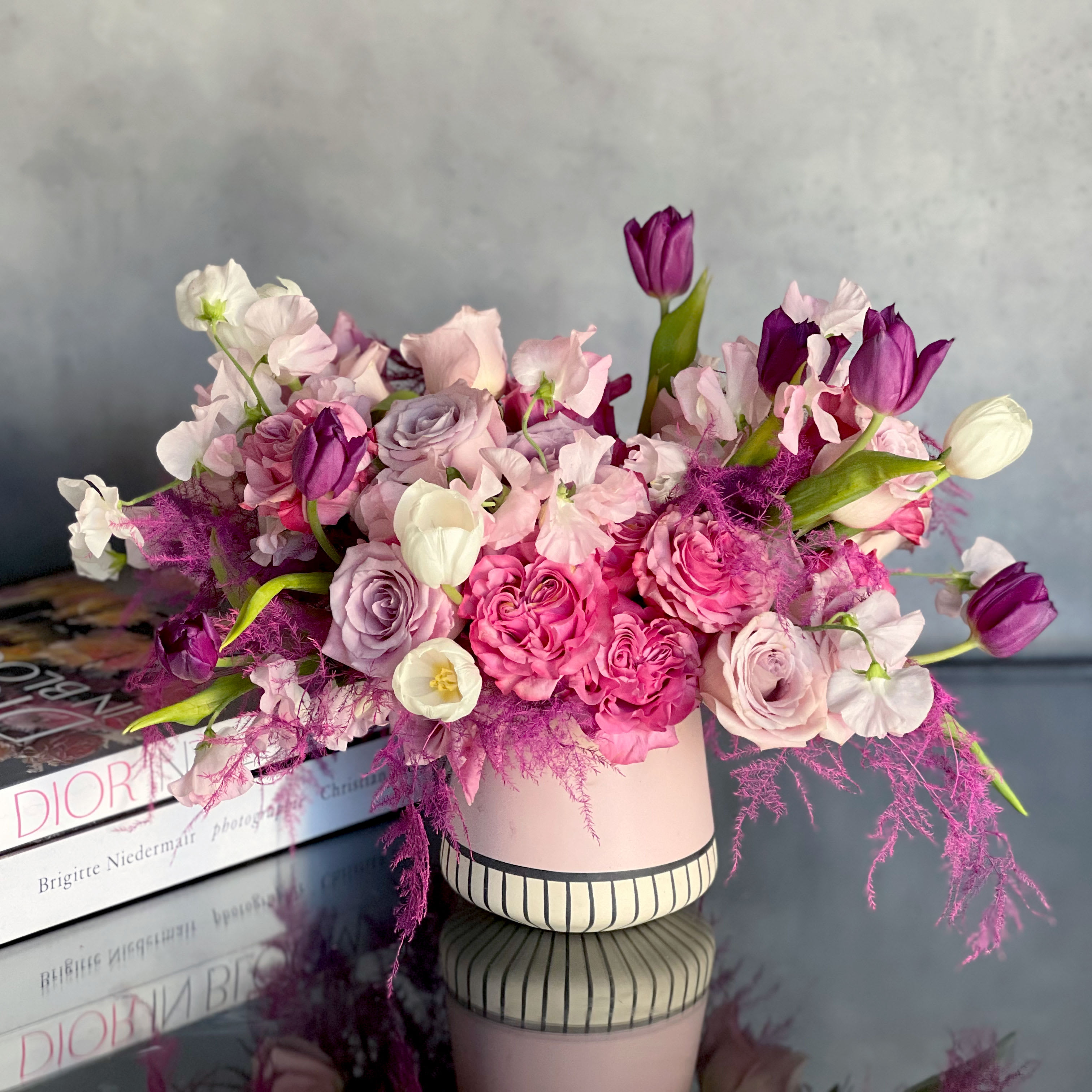 Sweet Pea  - Pasadena Florist - "Sweet Pea" is arranged with Sweet Pea flowers, Tulips, Ranunculus, Roses and other seasonal florals. All in various shades of pinks and purples placed within a pink ceramic vase.   