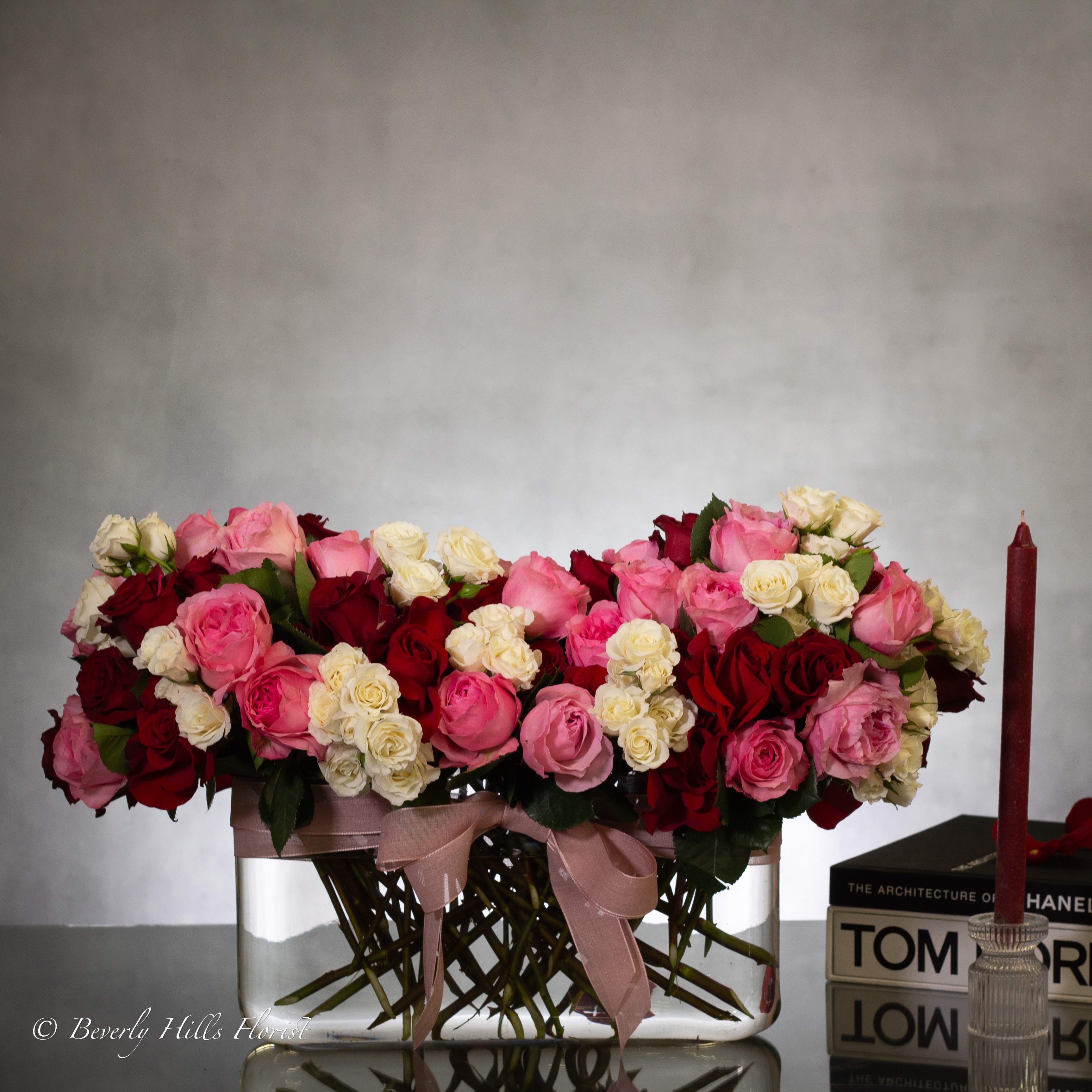 Love Language - Pasadena Florist - The perfect way to express your love this Valentine's Day. Experience unparalleled elegance with our stunning floral arrangements. The standard option has over 60 Blooms of Heart Shaped Floral  in a 8" wide, 22x17" glass vase. Our deluxe option offers over 100 blooms of exquisite roses in a 8" wide,32x22" vase. Show your love with a luxurious touch this Valentine's Day.