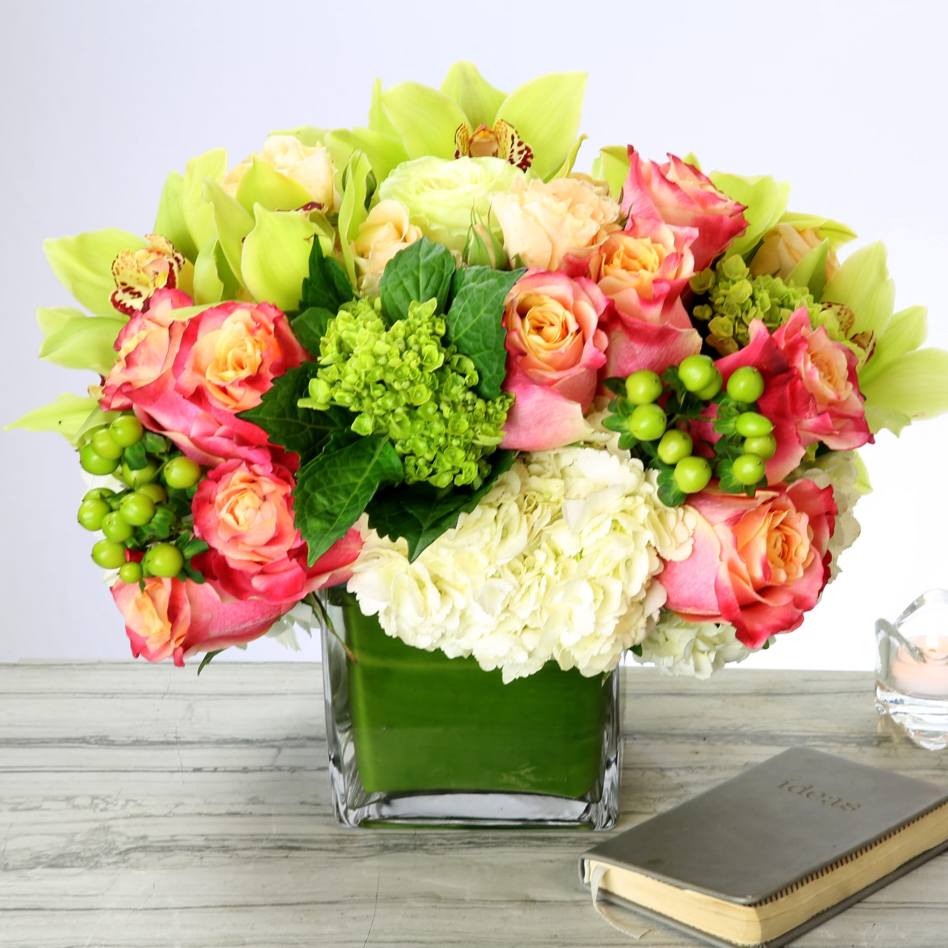 Happiness Blooms - Go ahead, let it pull you in! This inviting mix of imported Green Hydrangeas, South American Orange Roses and Dutch Orchids will instantly brighten your day.   Measurement   24" Round in a 6" glass Vase