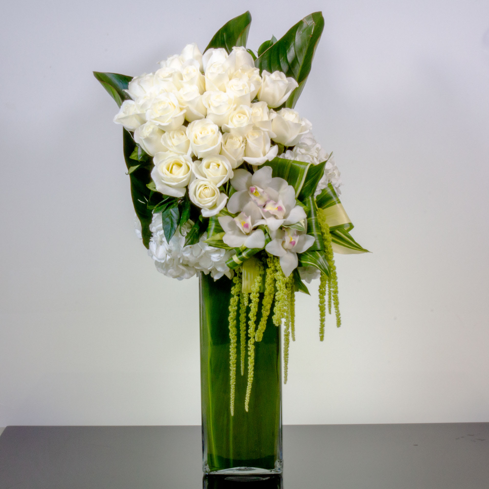 White Botanical Beauty - A modern accent for any occasion, this beautiful botanical sculpture blends snow white Roses with clouds of Hydrangeas and Dutch Cymbidium Orchids with unique greens for a peaceful, Eastern-inspired feel.  Approx: 40" Tall, container approx: 20" Tall   