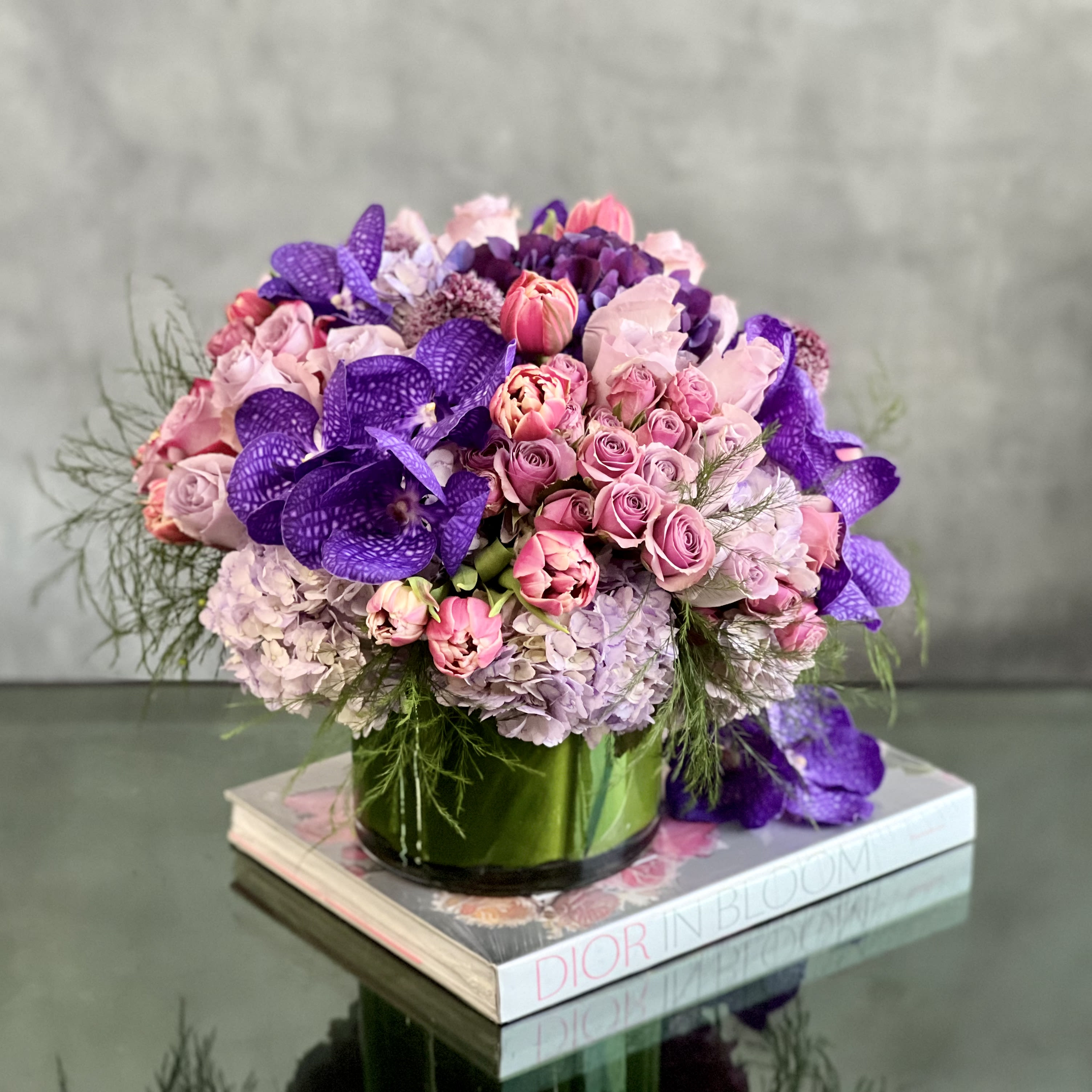 Where the Day Takes You - Our Where the Day Takes You arrangement is a gathering of lavender &amp; tulips, vanda Orchids surrounded by lavender hydrangeas inside a leaf lined cylinder vase. It's a beautiful way to express the sentiments you have inside your heart.  