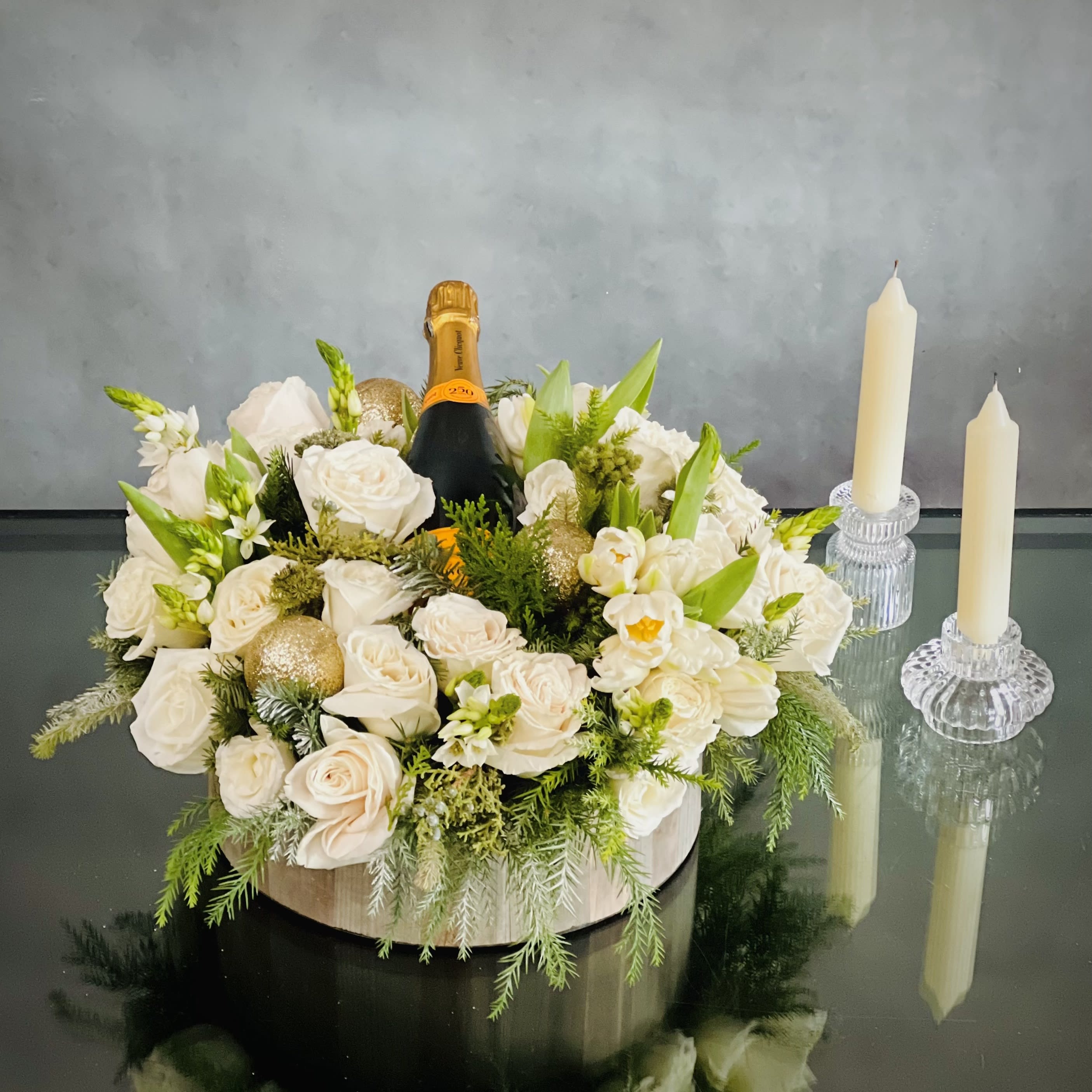 Celebratory Gift Box  - For a White holiday look, this elegant diversion combines soft Holiday Greens, whites Tulips and Roses that create an awesome Christmas design with a Bottle Of Champagne. A delightful arrangement that brings the joys of the season through beautiful and precious pastels.  Measurement:  14" round and 8" Tall