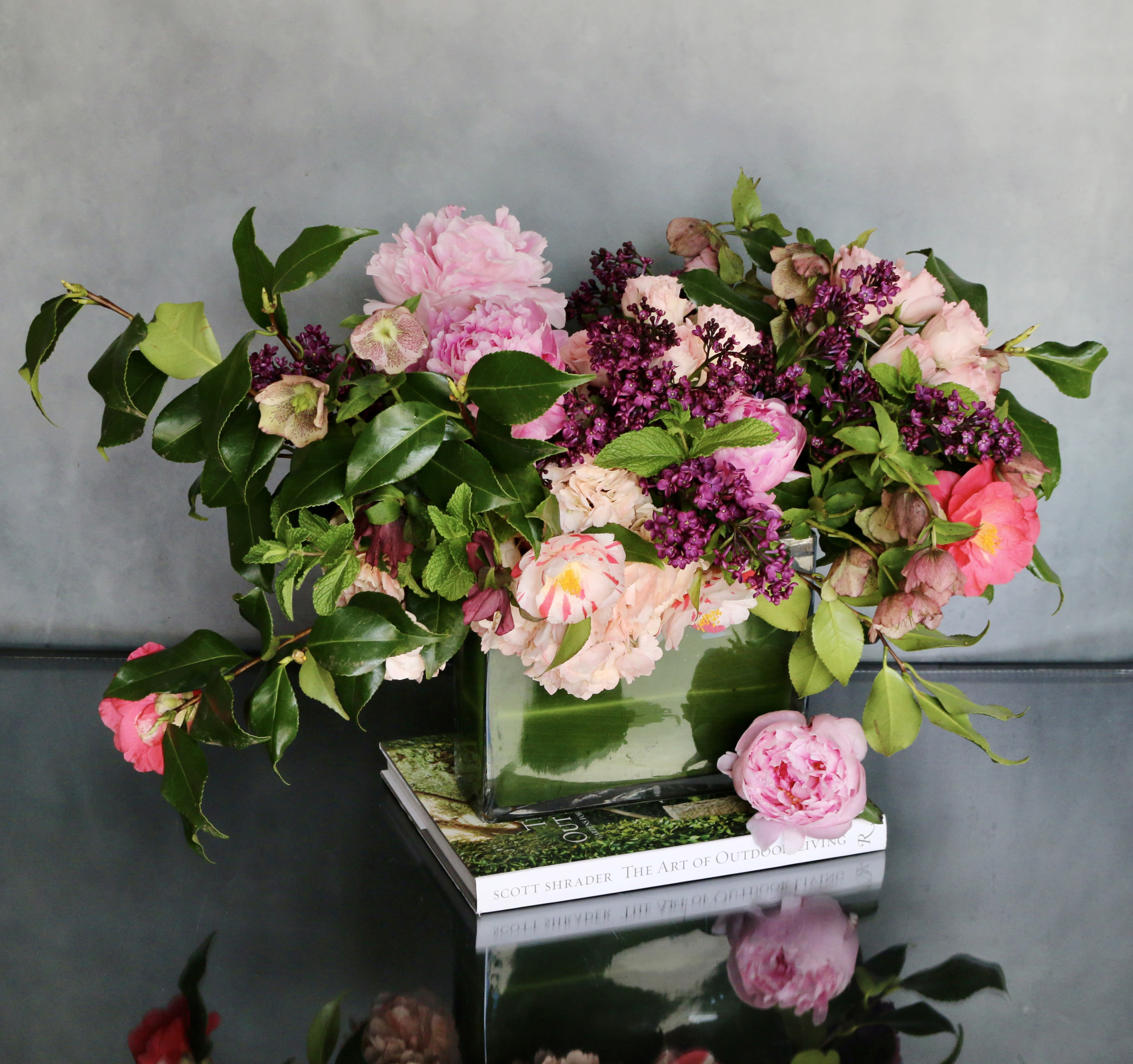 Eve's Garden  - "Eve's Garden" is a variety of pink florals, such as, Pink Peonies, Hellebores, Lilacs, Pink Hydrangeas and other delicate florals. Mixed in with a variety of seasonal greens in a leaf lined glass vase.   Measurements: Vase: 9 x 10 Arrangement: 16 x 16